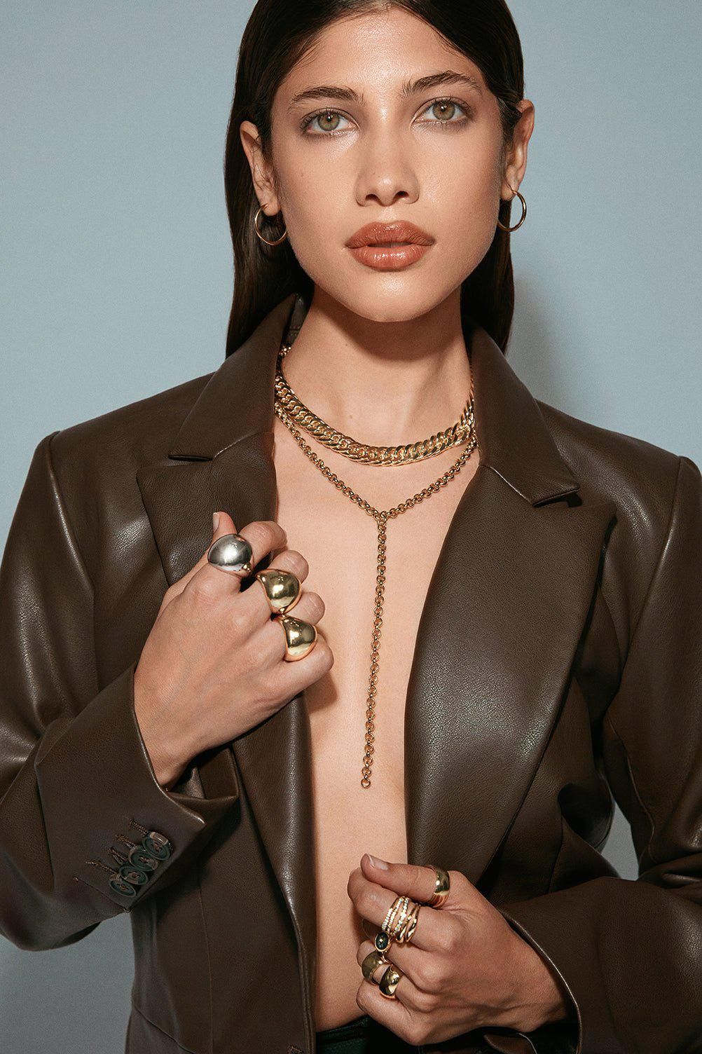 a woman wearing a brown leather jacket and gold jewelry