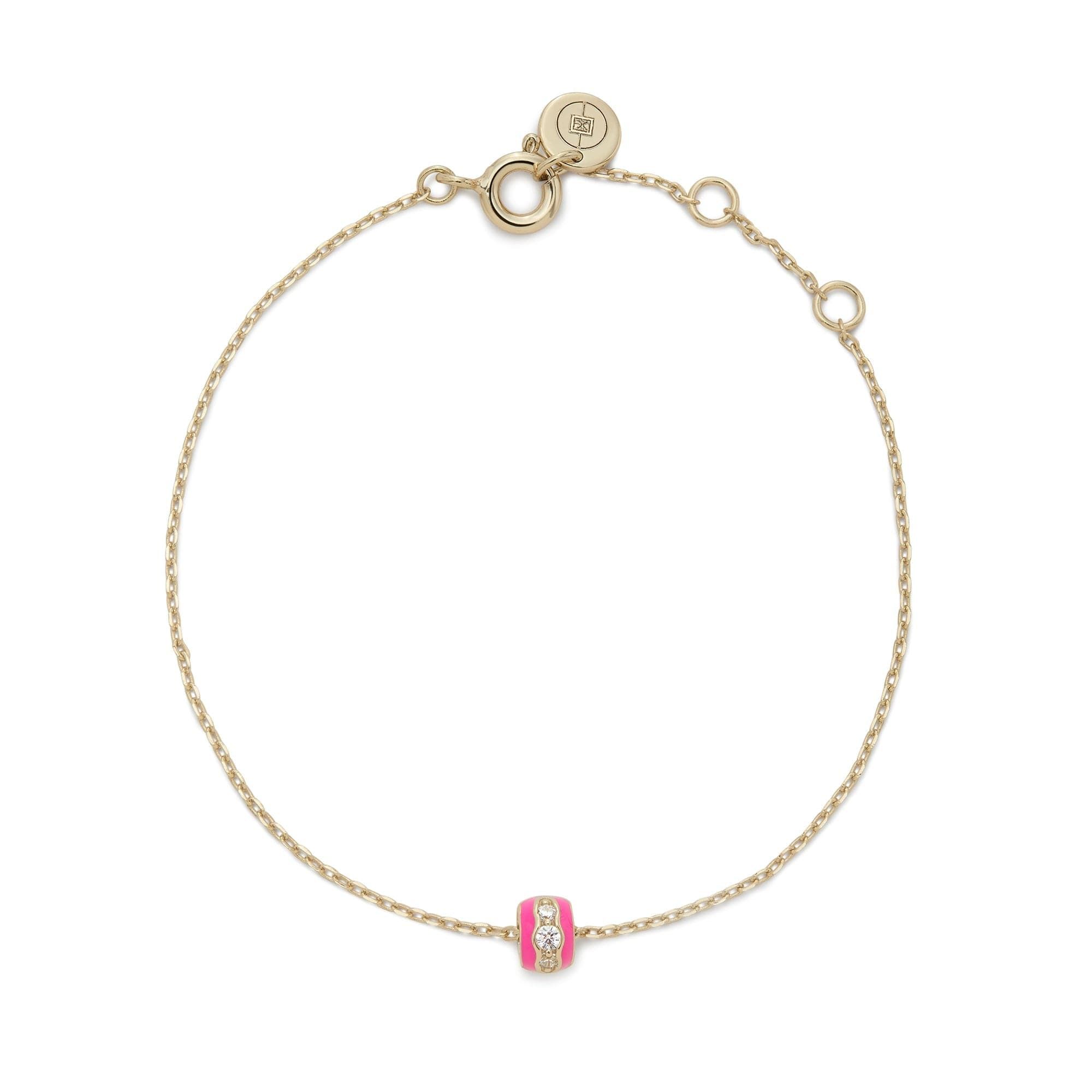 a gold bracelet with a pink bead