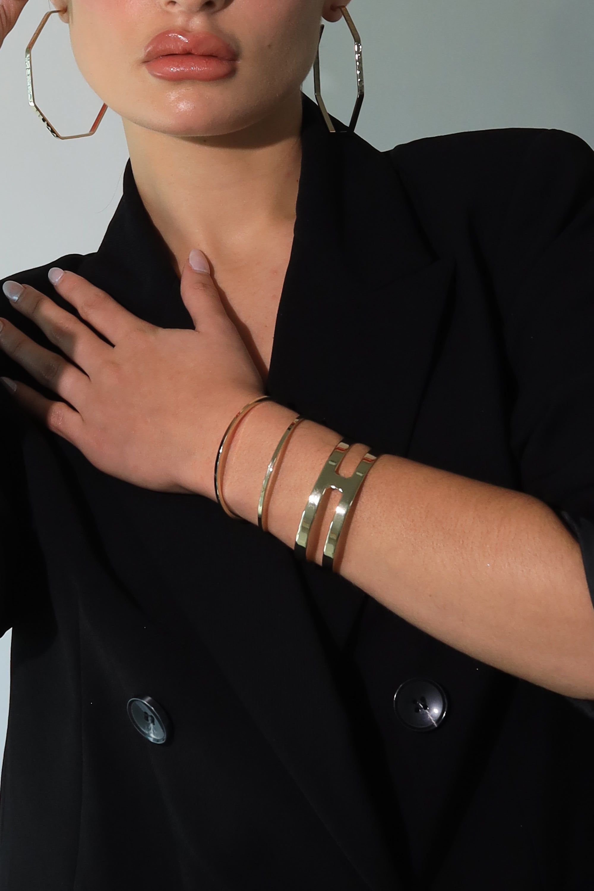 a woman wearing a black jacket and gold bracelets