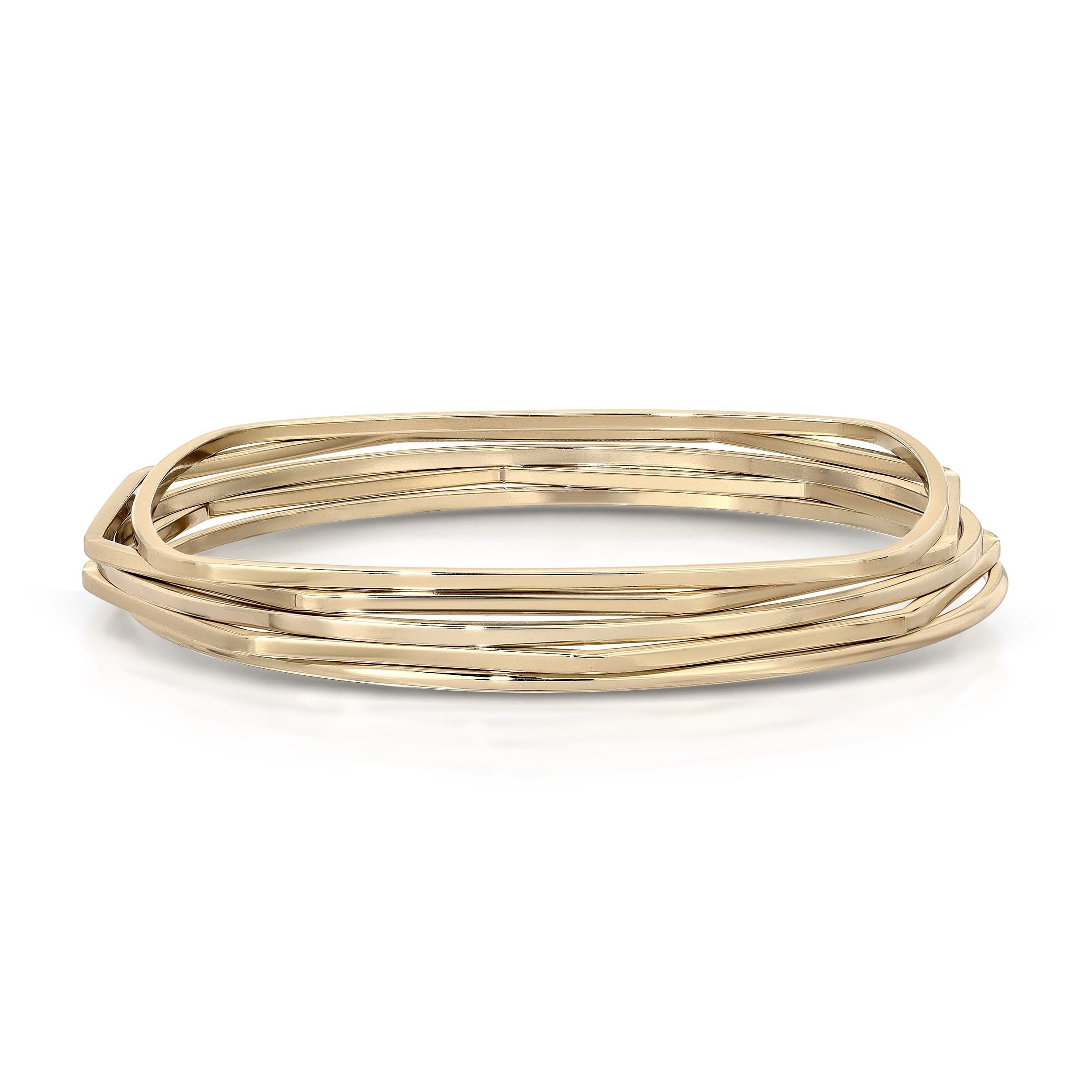 a stack of thin gold bracelets on a white background