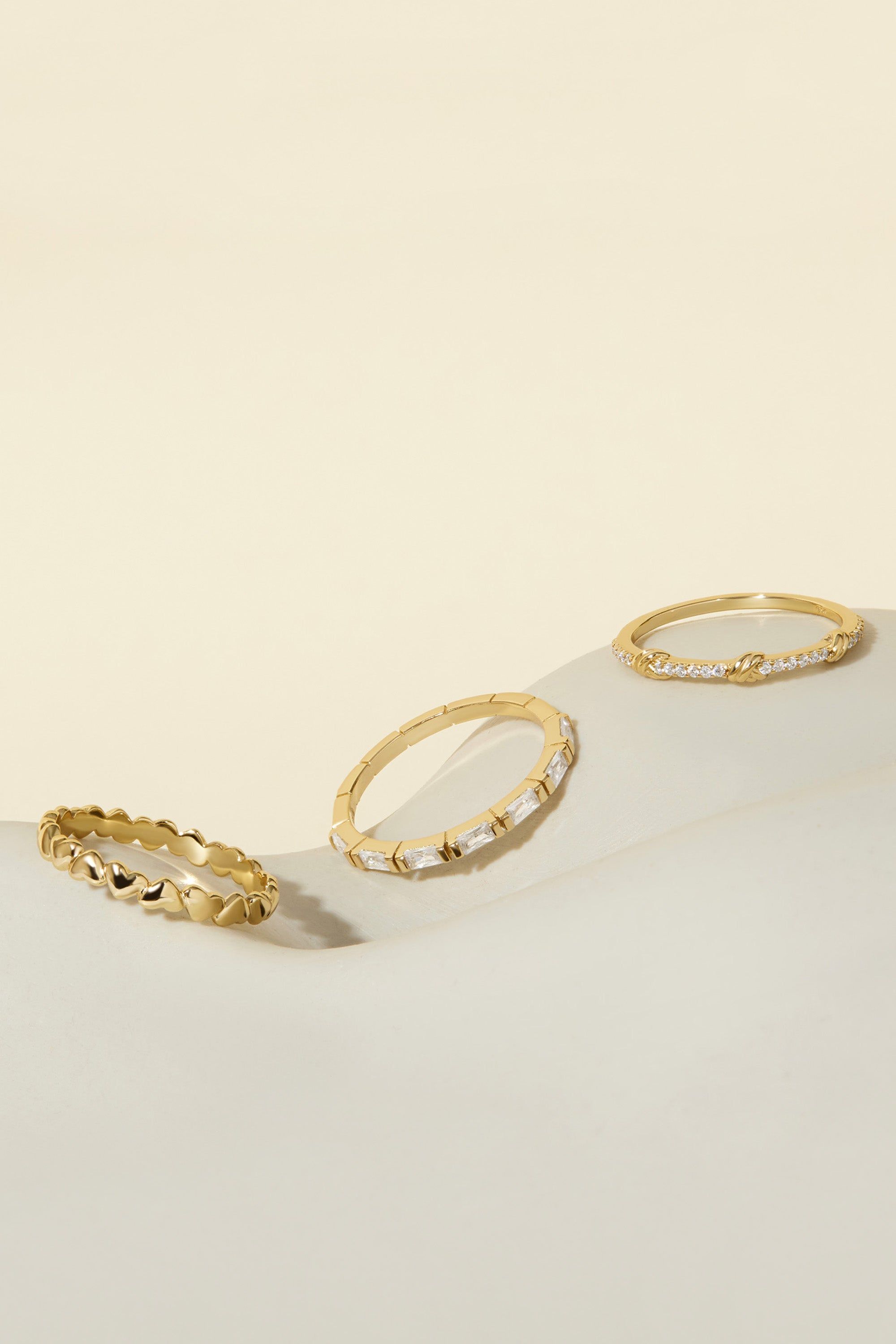 three gold rings sitting on top of a white surface