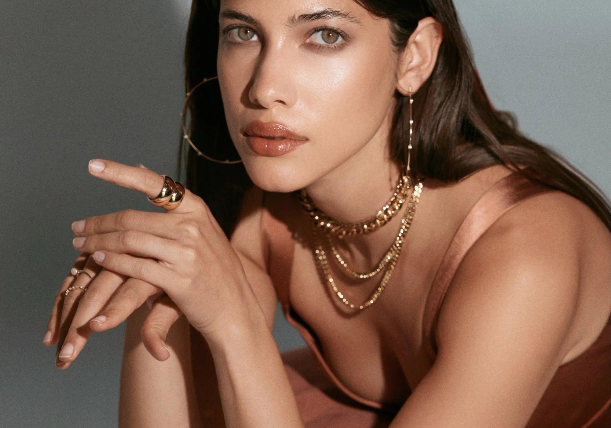 A woman in a gold dress adorned with gold jewelry, looking elegant and glamorous.