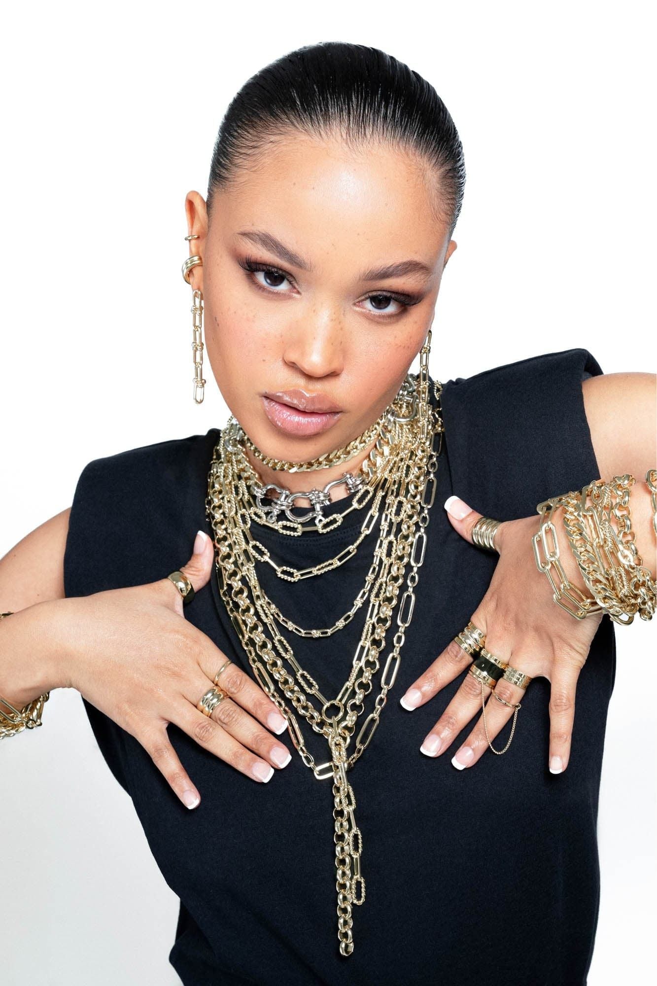 Woman showcasing the Arya Bracelet with gold jewelry and slinky curb chain design