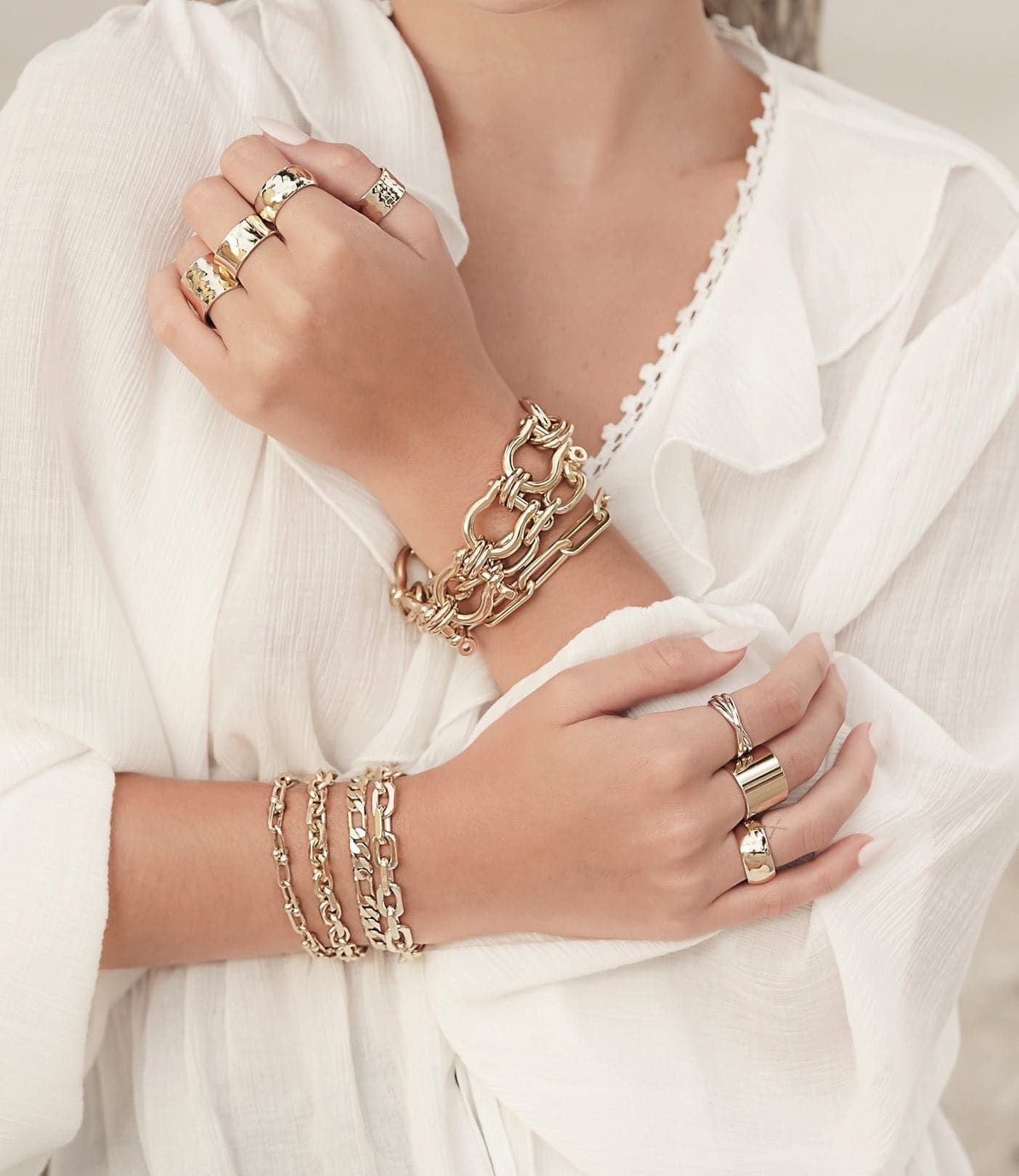 Woman’s hands showcasing the Baby Axel Bracelet with gold jewelry and figaro chain