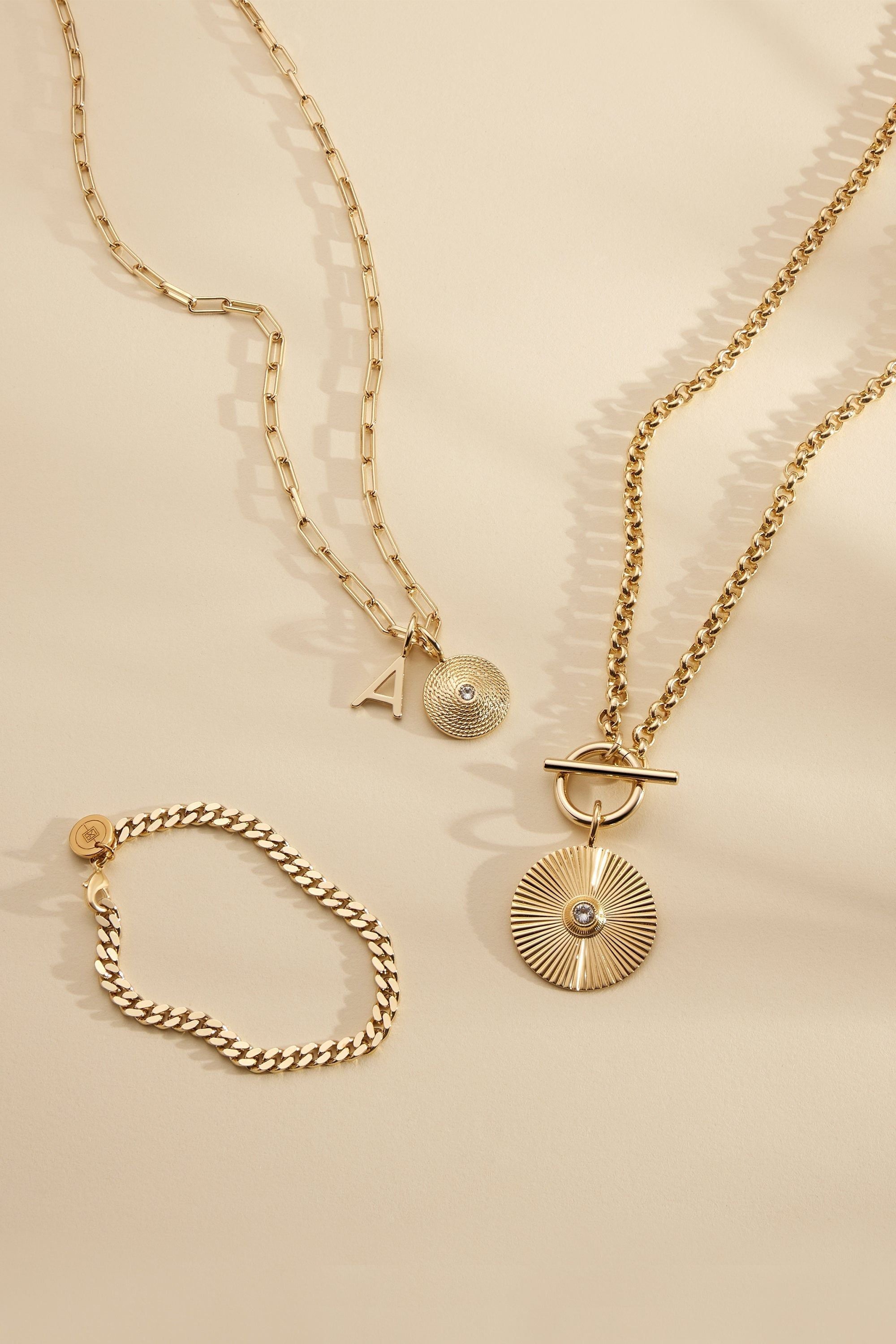 Gold-toned jewelry set featuring the Catherine Charm Necklace with elongated link chain and Zena pendant