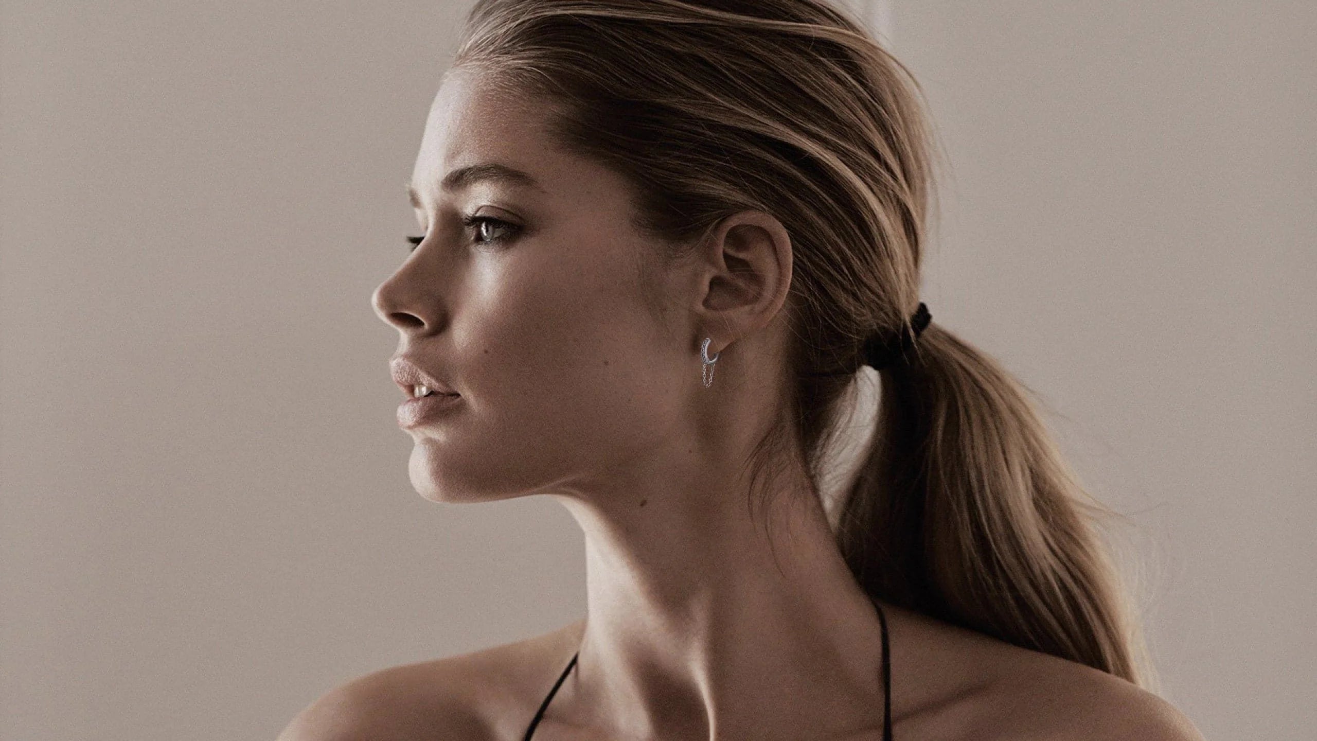 Woman with ponytail wearing 12.5mm Diamond and White 14K Gold Huggies with Chain