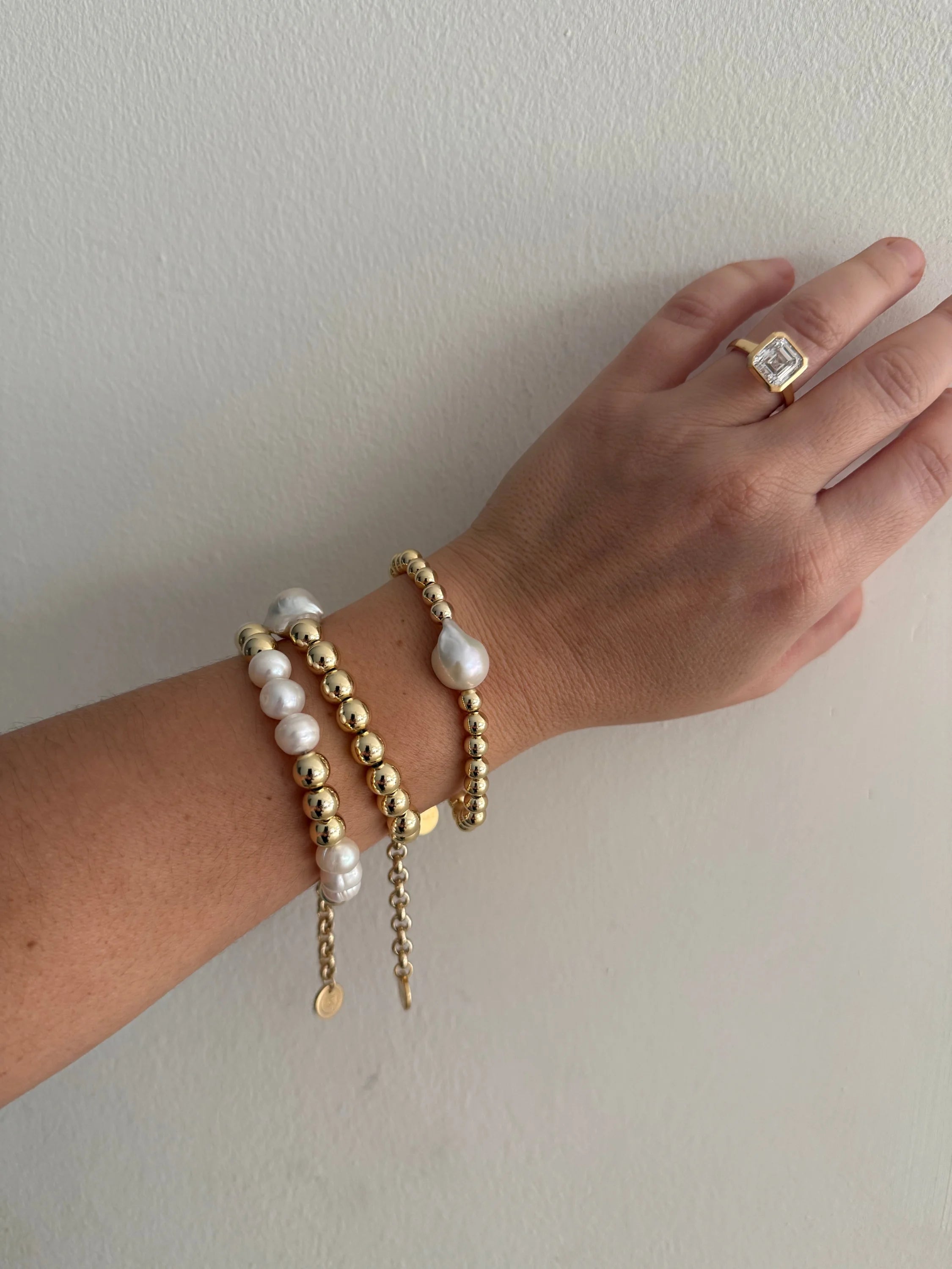 Woman’s hand showing off Petra Pearl and Bead Bracelet with gold jewelry
