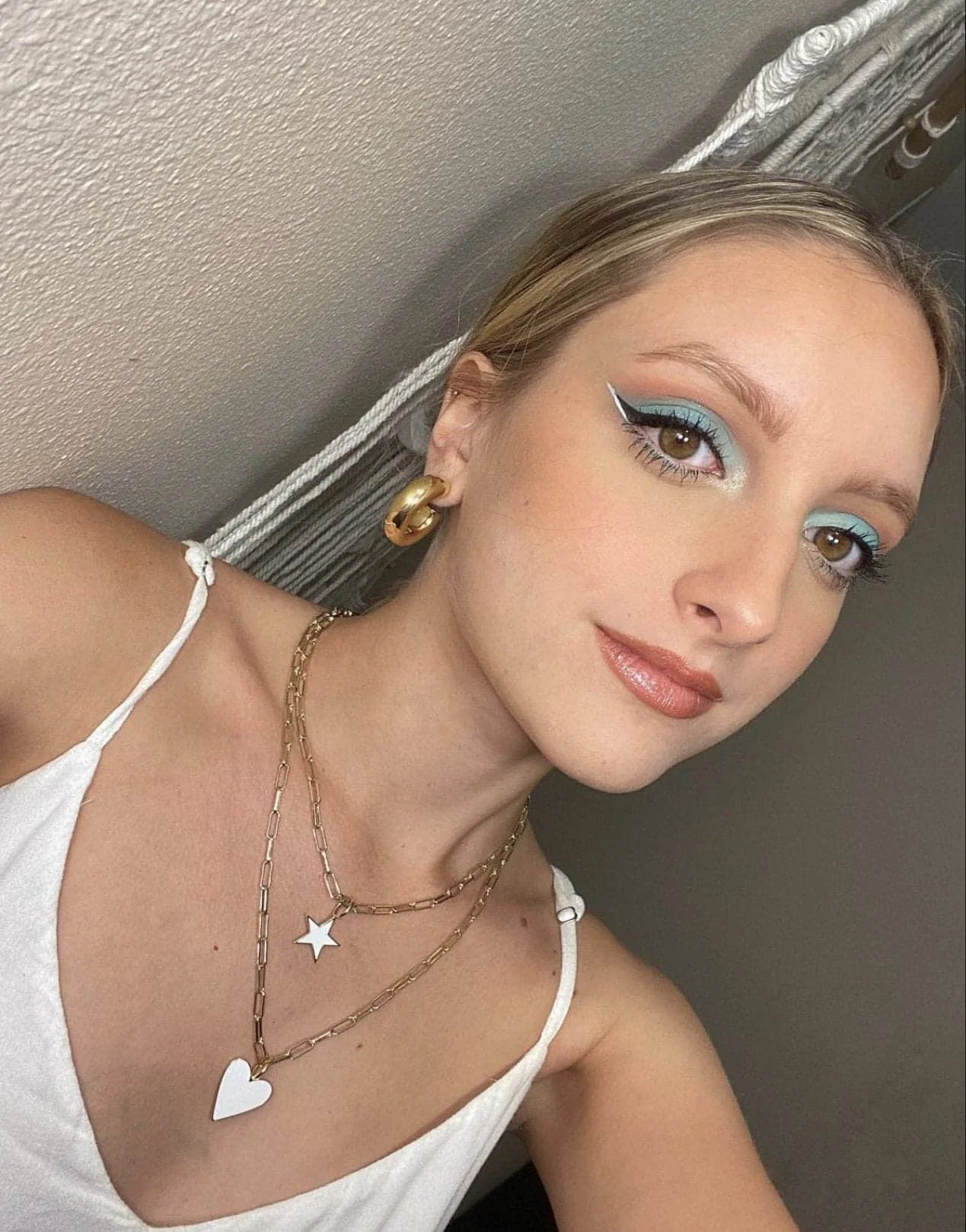 Woman with colorful eye makeup and layered necklaces showcasing the Enamel Samara Charm