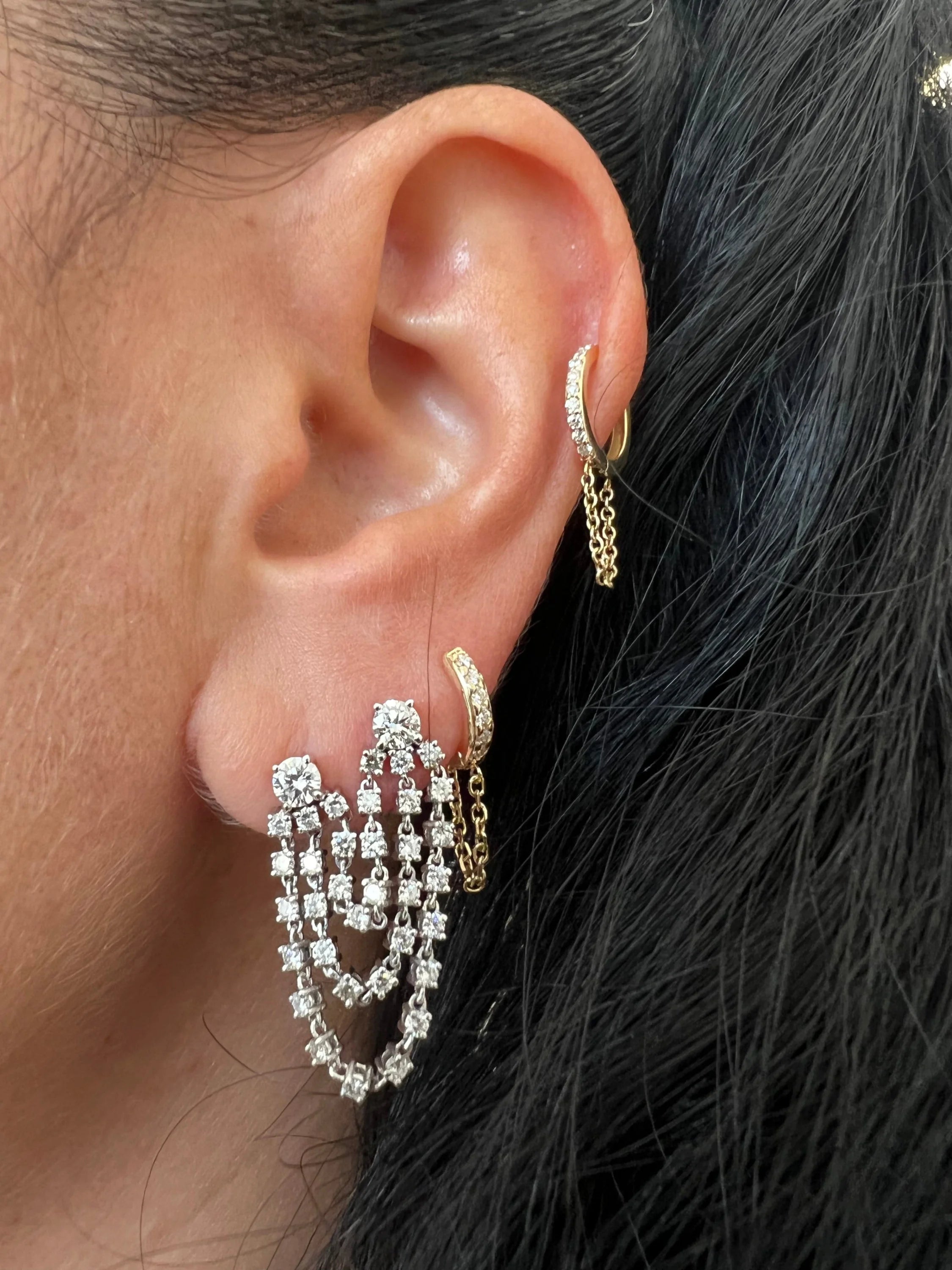 Ear with multiple sparkling diamond earrings wearing the Double Diamond Chain Earring jewelry