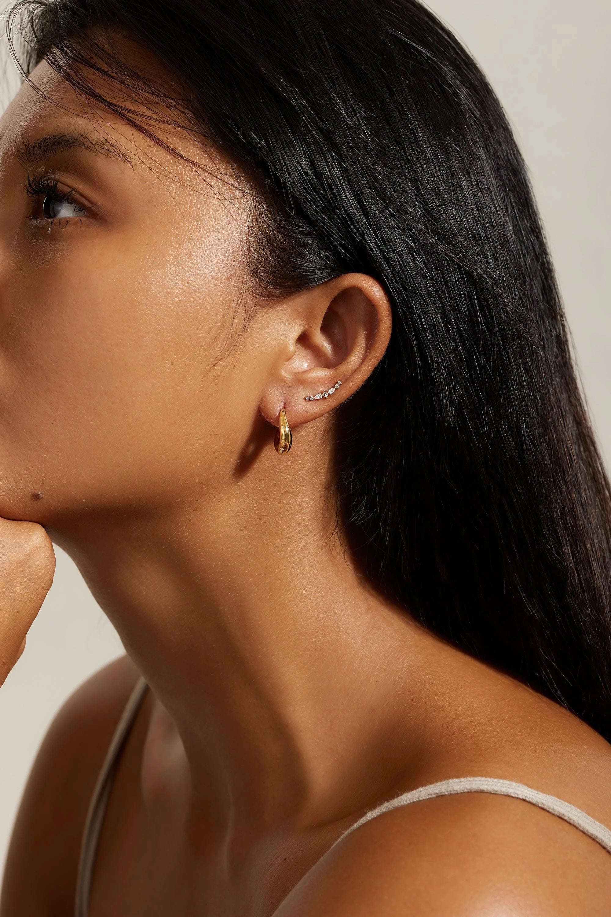 Woman with multiple ear piercings wearing gold hoop and stud earrings, showcasing Multi Shaped CZ Ear Crawl