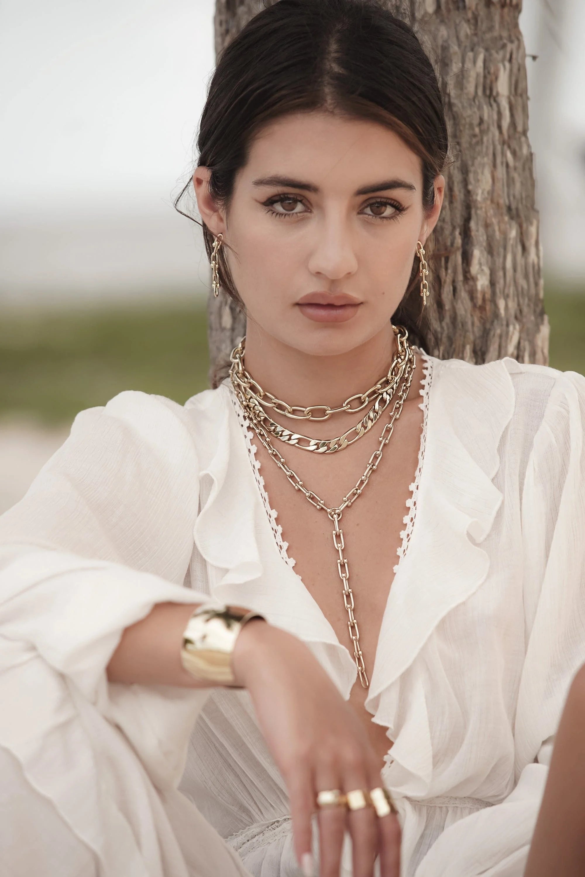 Woman showing off shiny gold Alana Necklace jewelry perfect for stylish looks