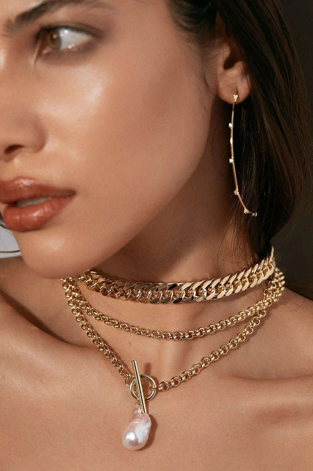 Woman wearing gold jewelry showcasing the Arya Necklace accessory