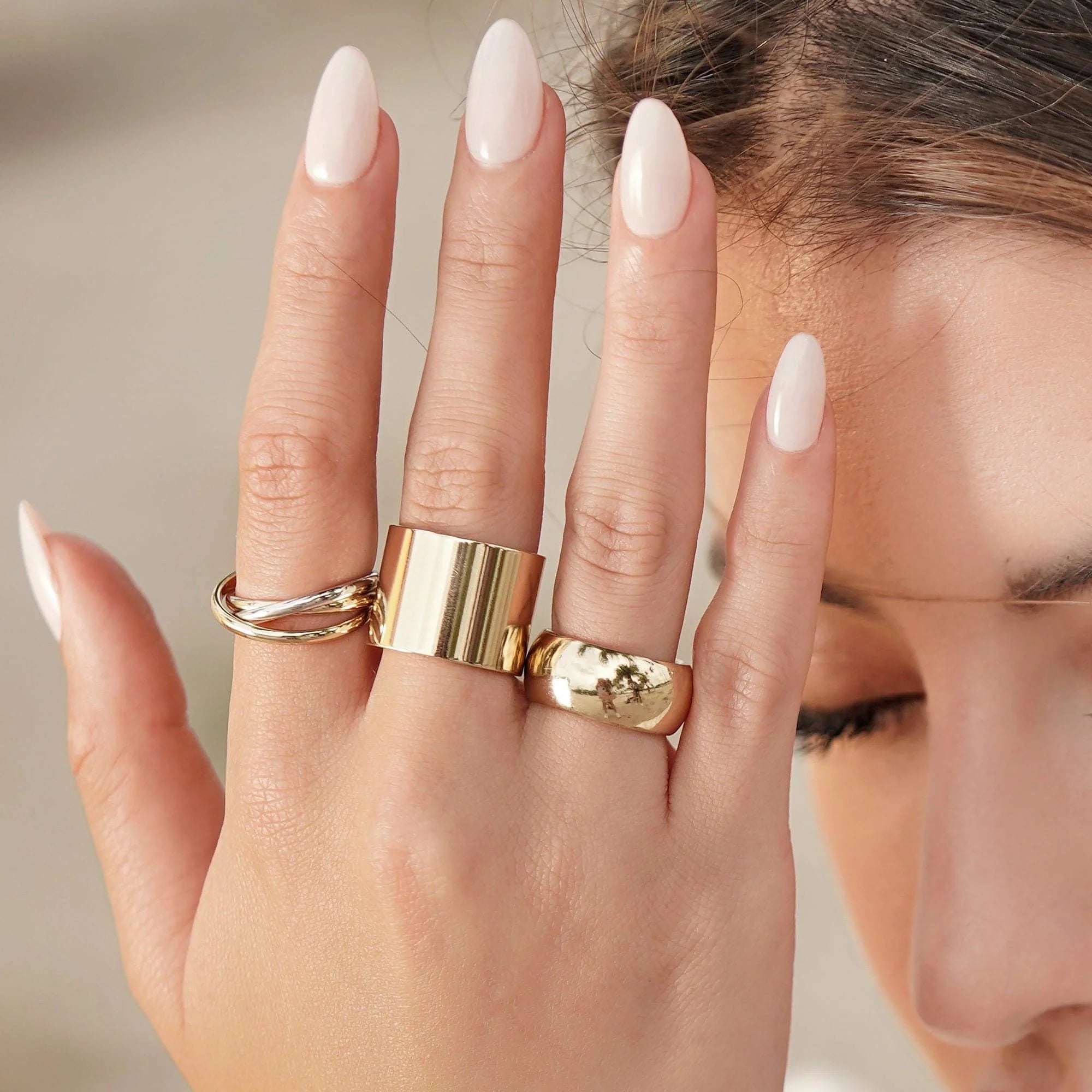 Close-up of a Hand wearing a 9.5mm Domed Ring with shiny gold rings