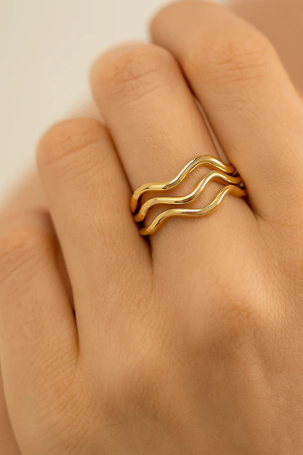 Three wavy gold rings on a finger showcasing the Super Thin Wavy Ring design
