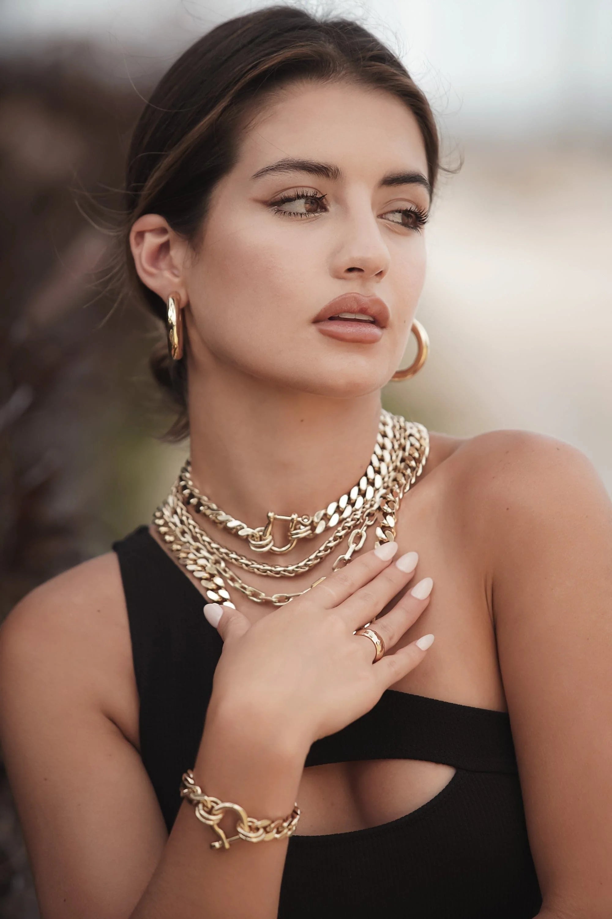 Woman wearing gold jewelry showcasing the Roxy Bracelet style and elegance