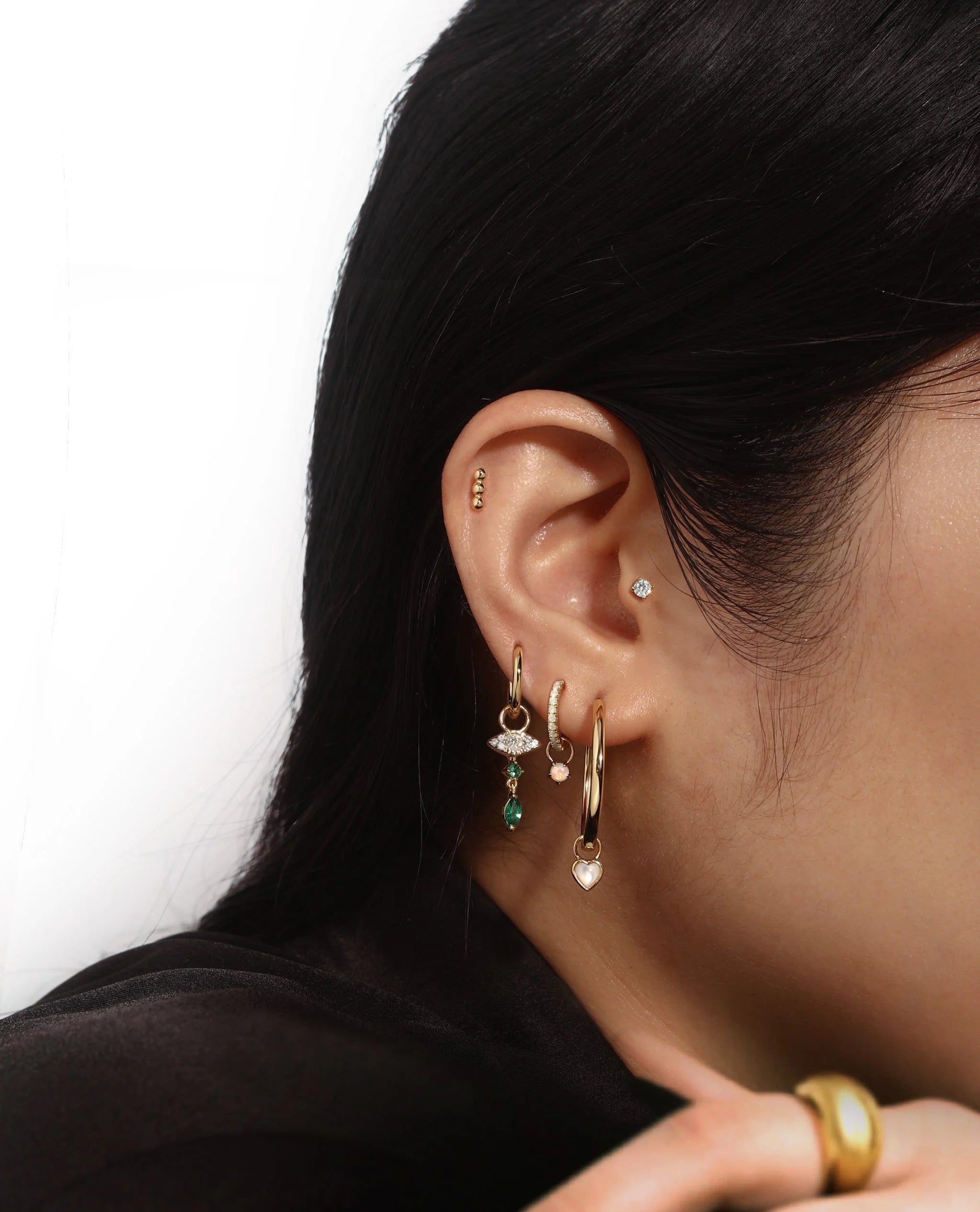 Ear with gold earrings from Mother Of Pearl Heart Hoop Charm demi-fine collection hoop charms plated + e-coating