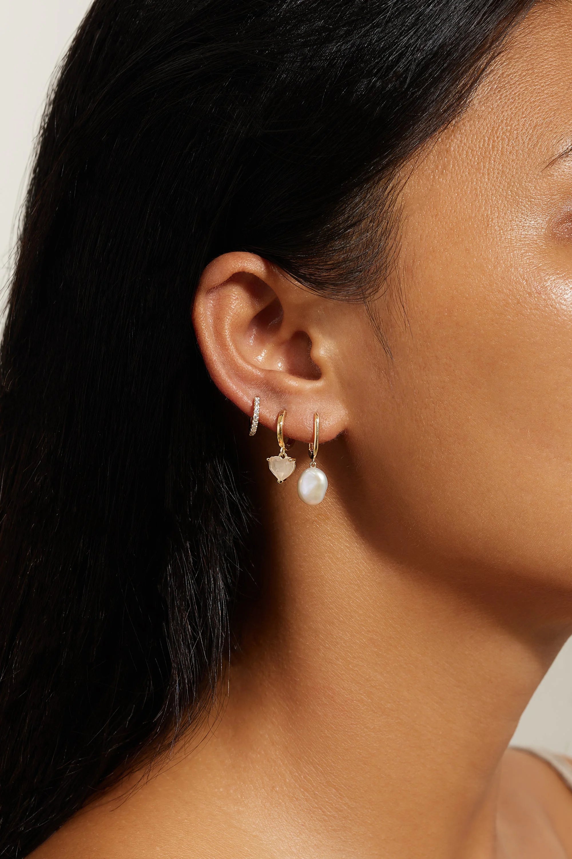 Ear with multiple 14k gold vermeil oval huggie hoops and vermeil baroque pearl drops