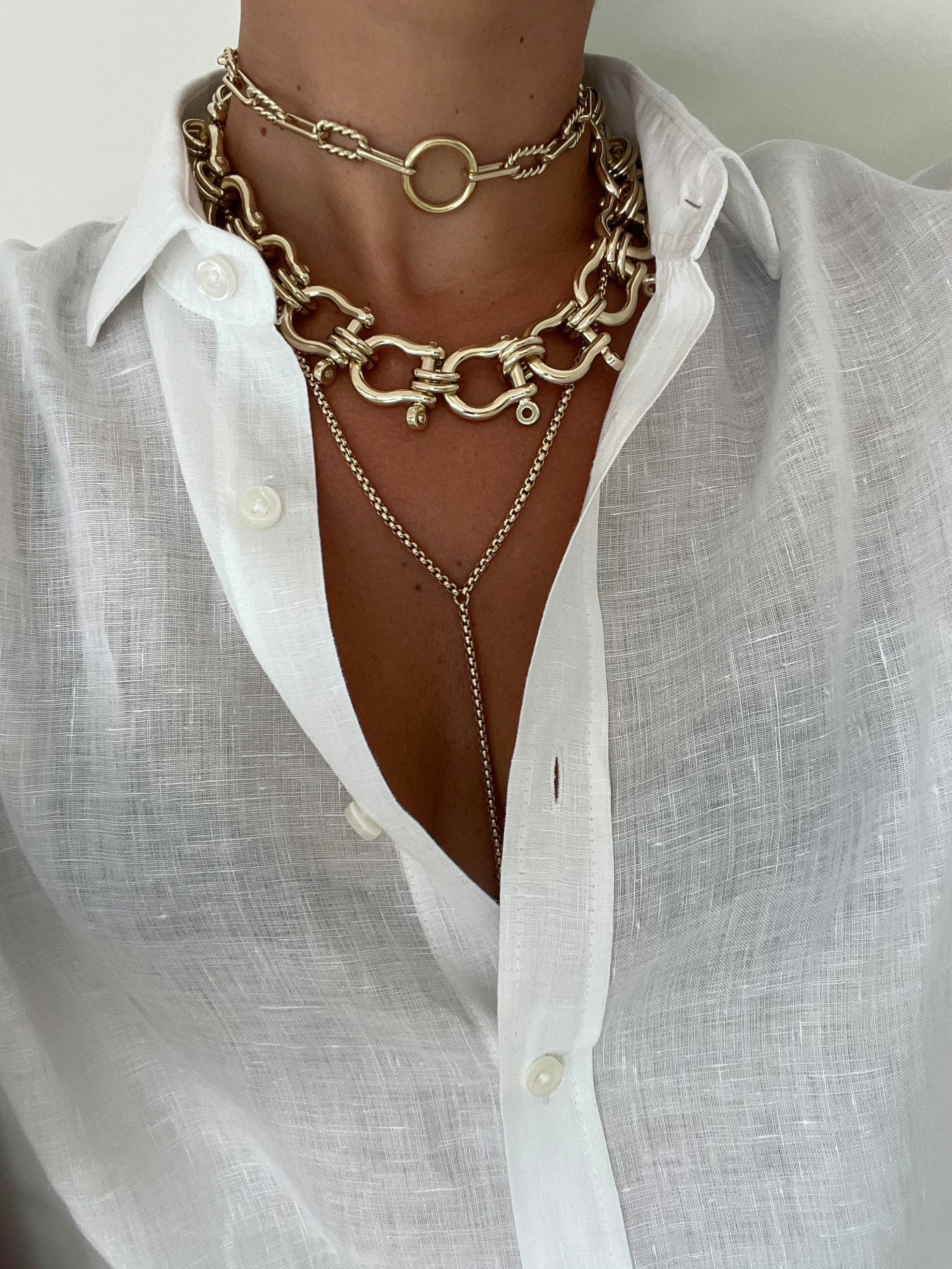 Eliza Necklace features gold layered necklaces with twisted link chains and a white linen shirt