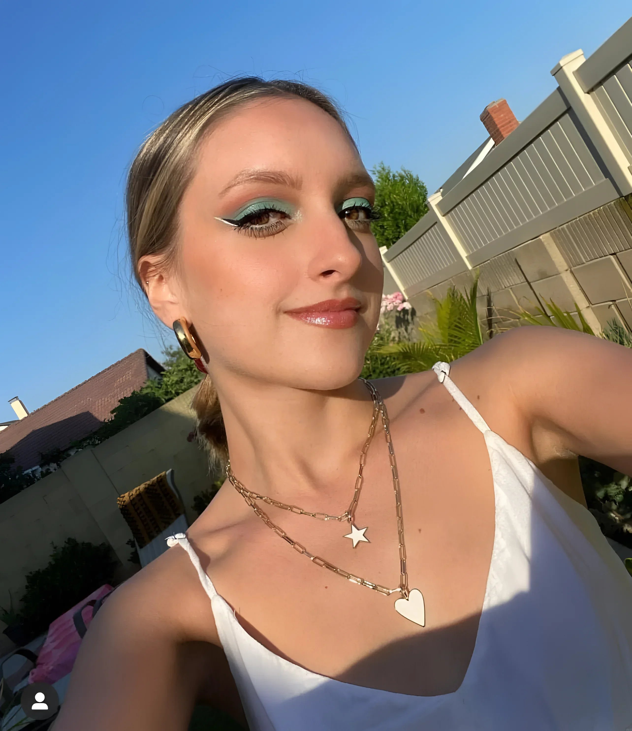 Blonde woman with blue eyeshadow wearing layered gold necklaces and Enamel Samara Charm