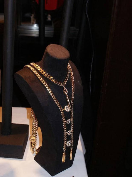 Gold chain necklaces elegantly arranged on a black display for Blazers & Bellinis blog.