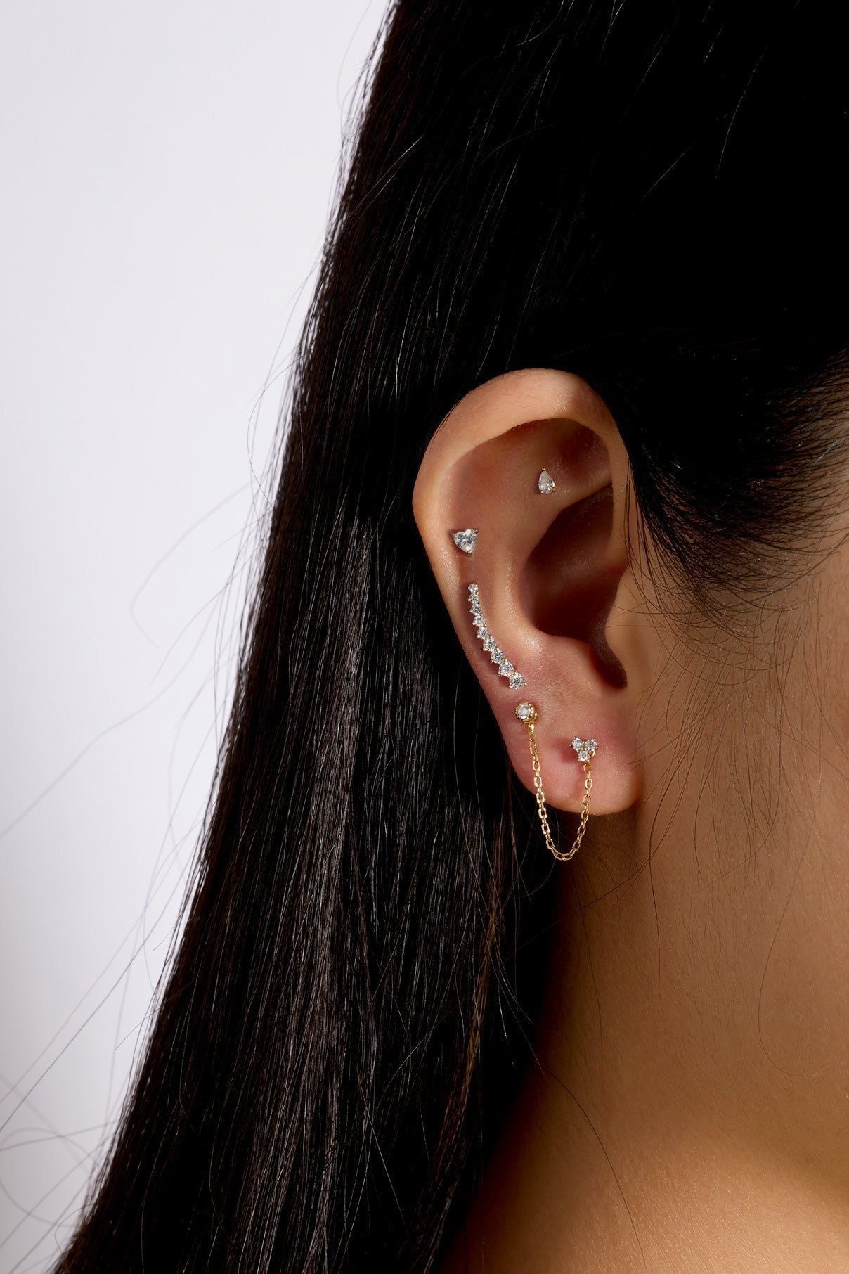 Ear adorned with multiple sparkling earrings from the Graduated Cz Bar Ear Crawl in 14k gold vermeil