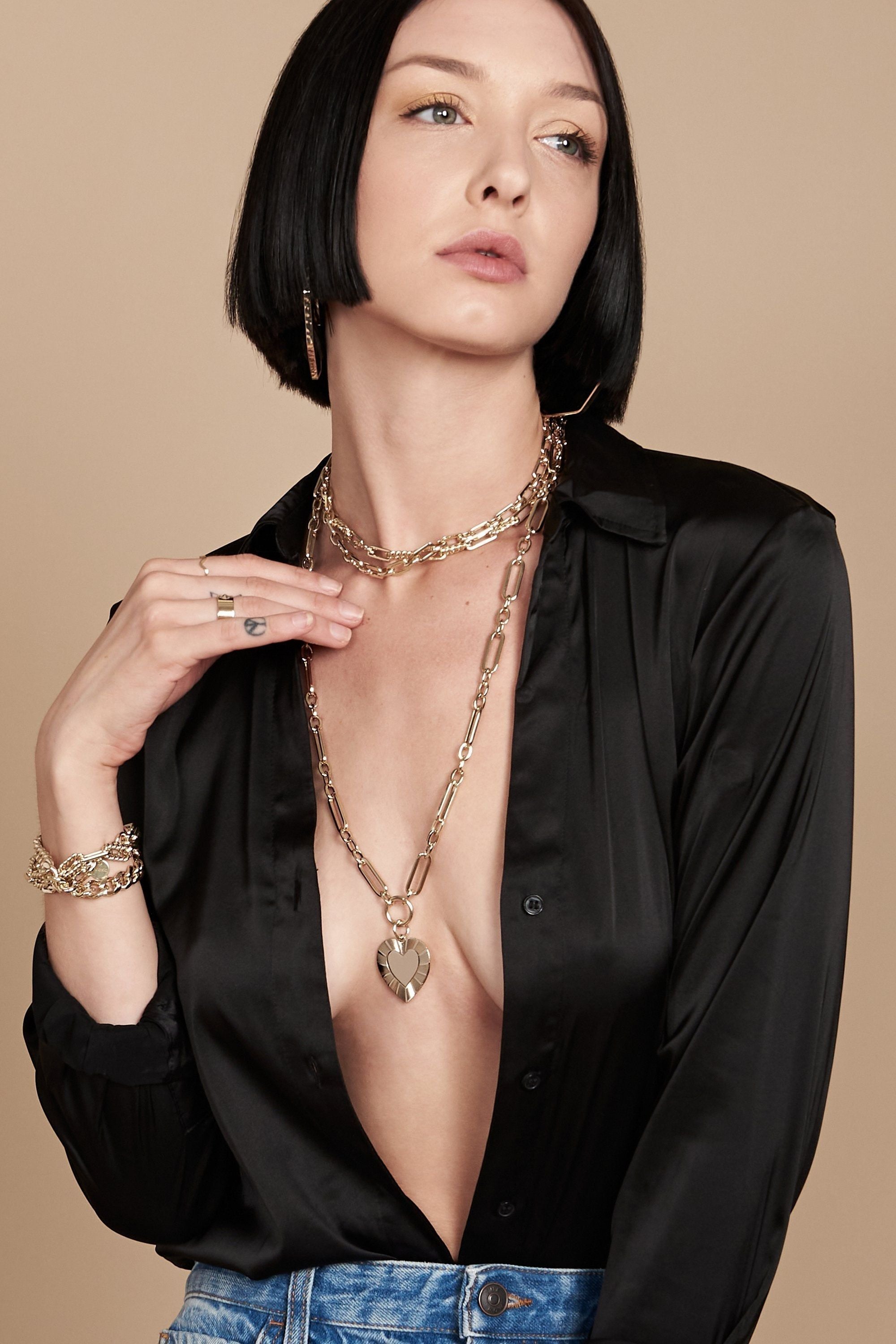 Woman showcasing Hildegard Pendant and brass plated 14k gold jewelry with elegance