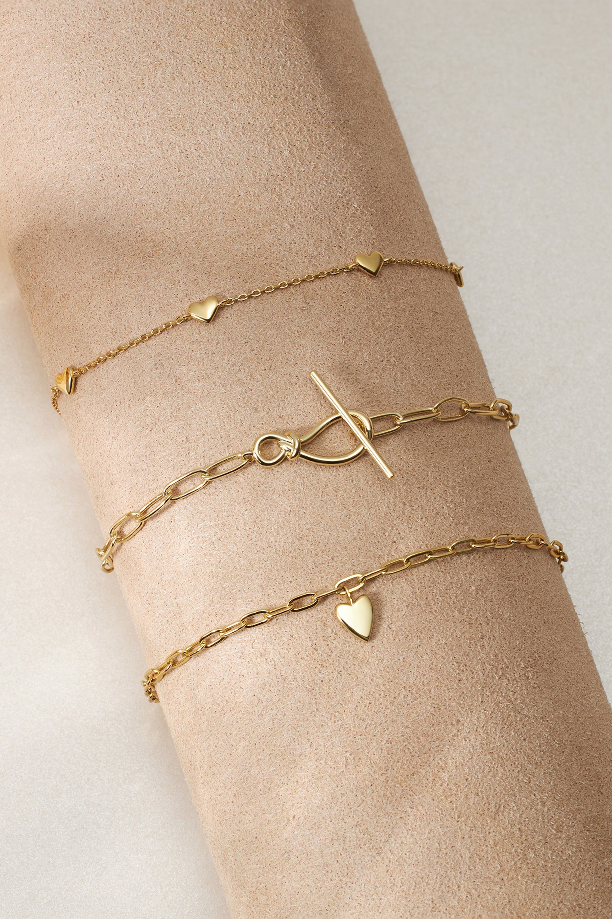 Gold-toned layered bracelet featuring knot toggle clasp and paperclip chain design