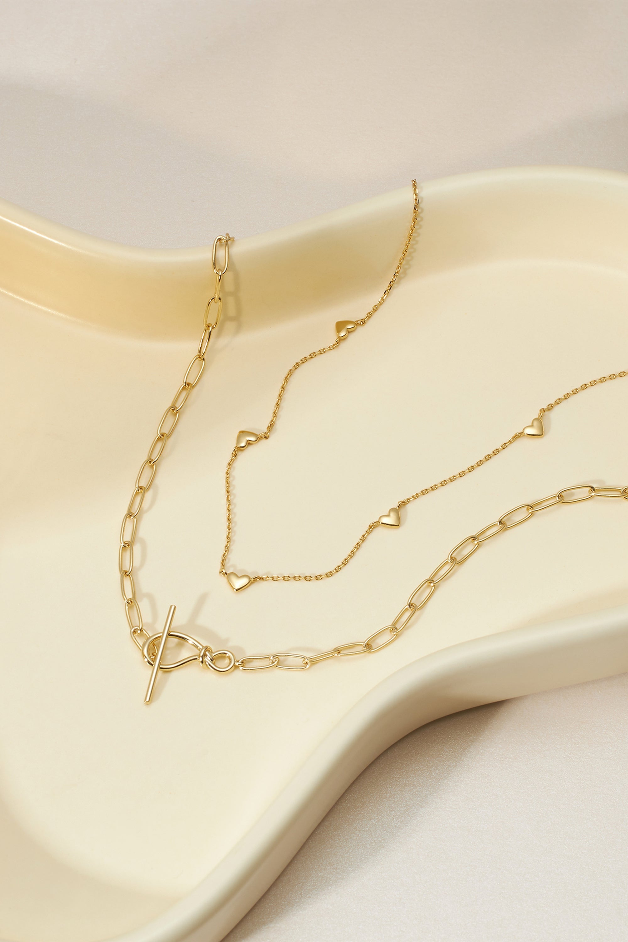 Two gold necklaces featuring a Knot Toggle & Paperclip Chain design in 14k gold plated