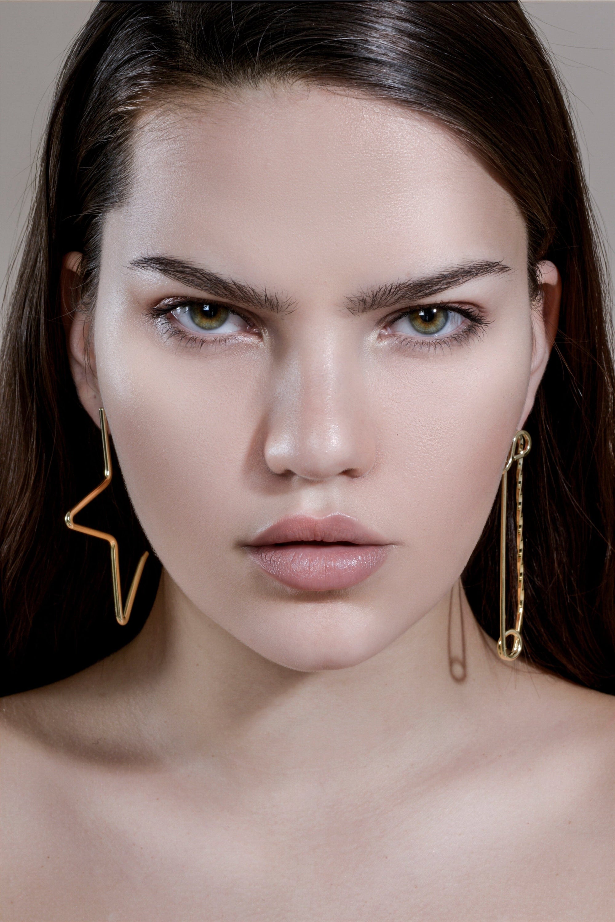 Stern-faced woman wearing Large 1/2 Star Earrings in 14k yellow gold