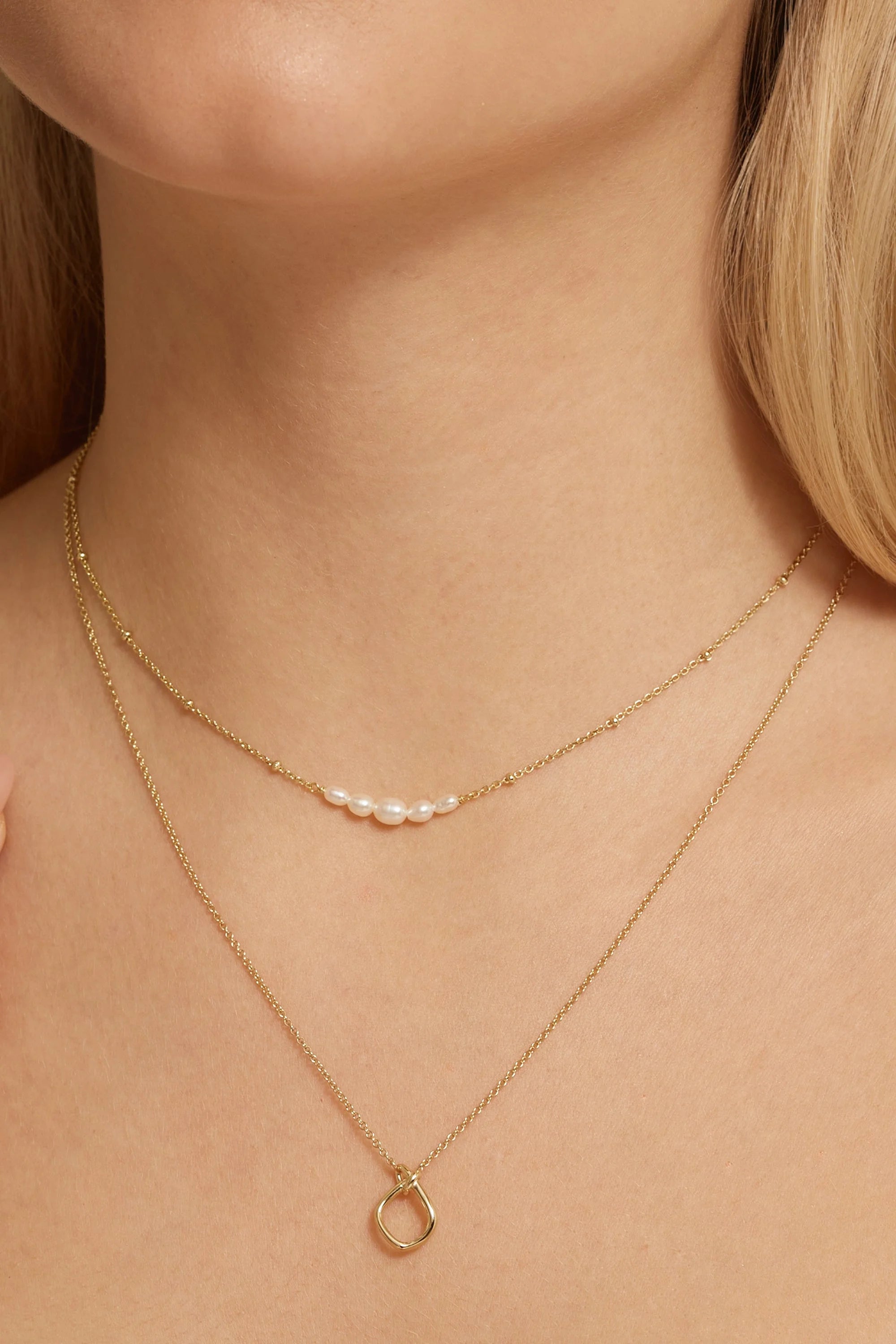 Layered 14k gold plated necklaces with pearl and circle pendants in the Love You Knot Necklace