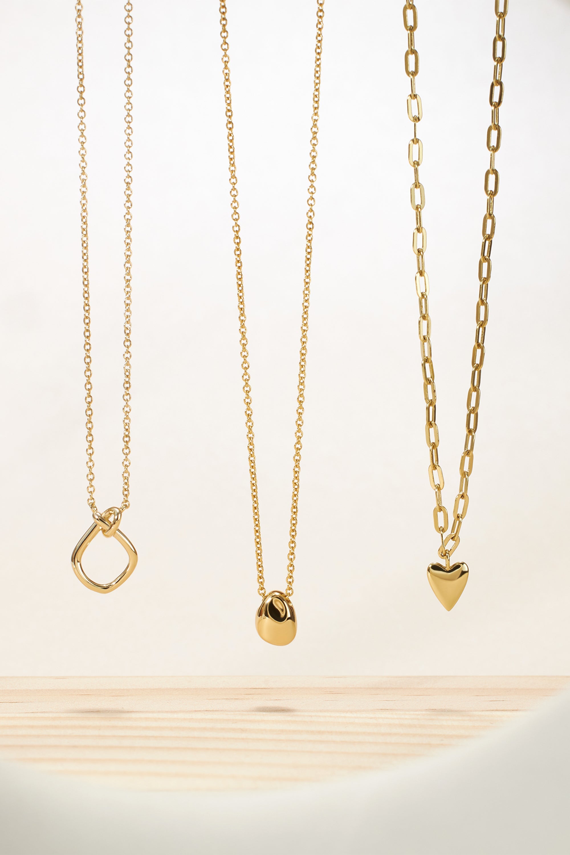 Three stunning gold necklaces featuring the Love You Knot Necklace design in 14k gold