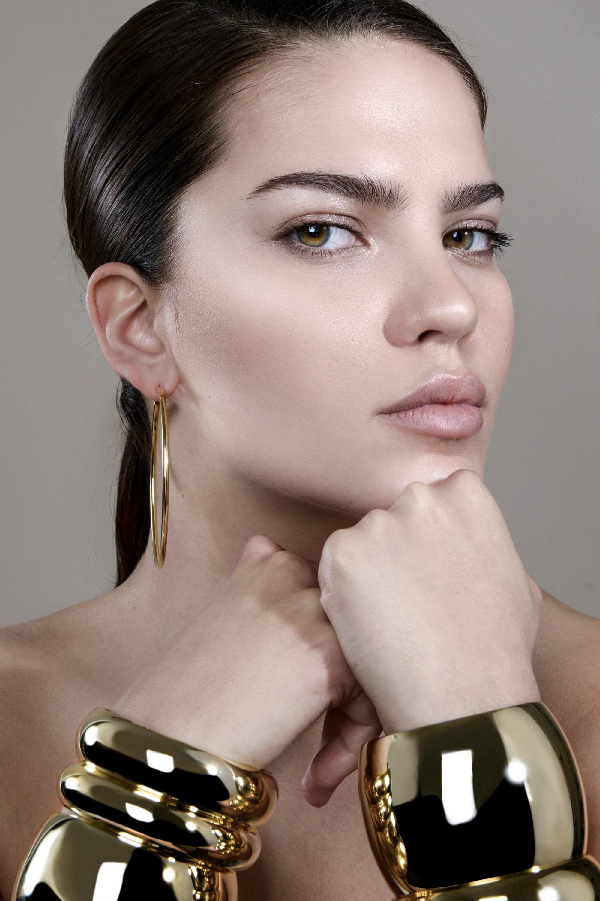 Woman wearing Medium Athena Bangle in recycled brass with inch wide domed design