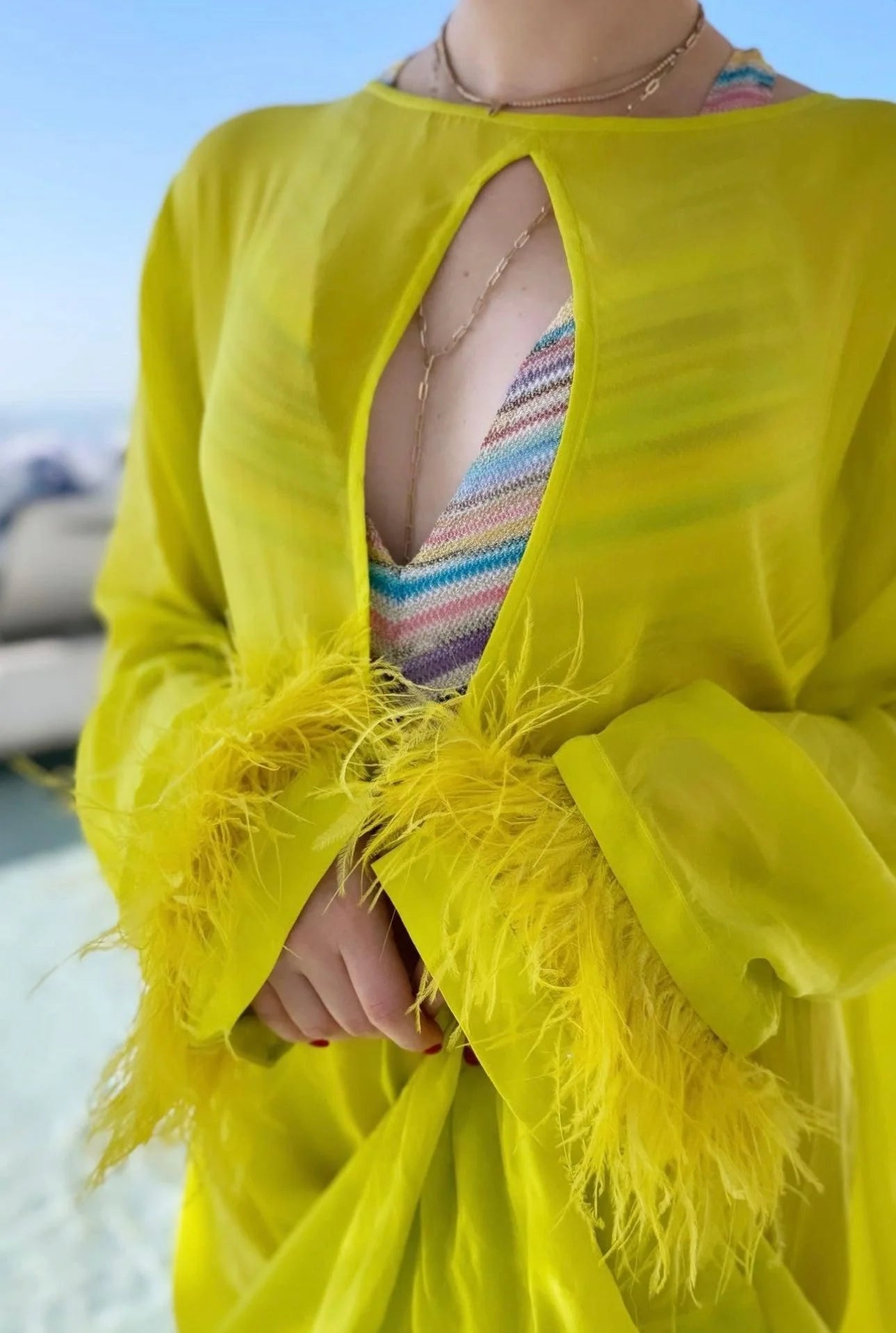 Yellow feather-trimmed cover-up with medium link chain lariat in recycled brass plated material