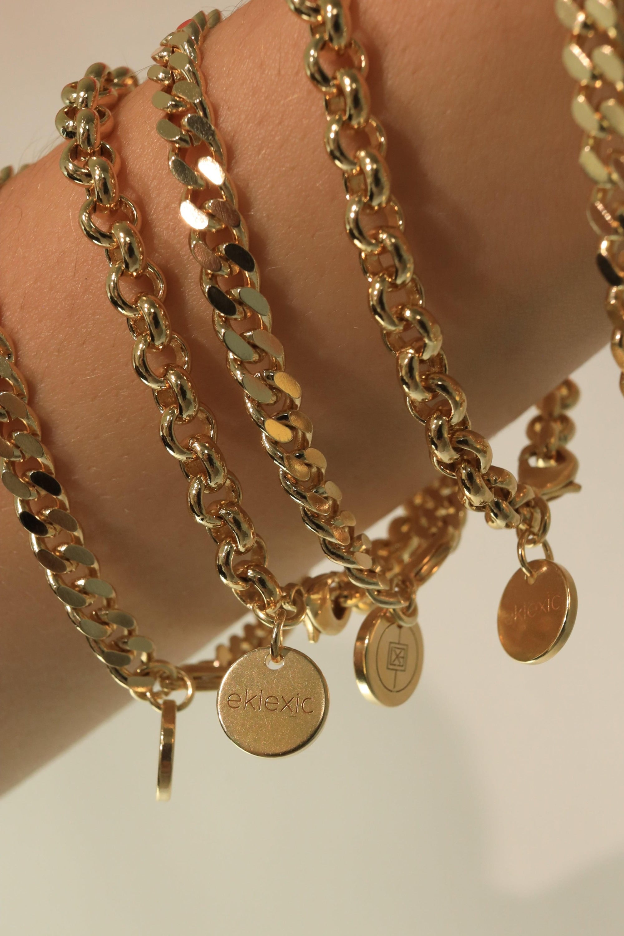 Gold chain bracelets with circular pendants featuring Ecoat Micro Rolo and rhodium plating