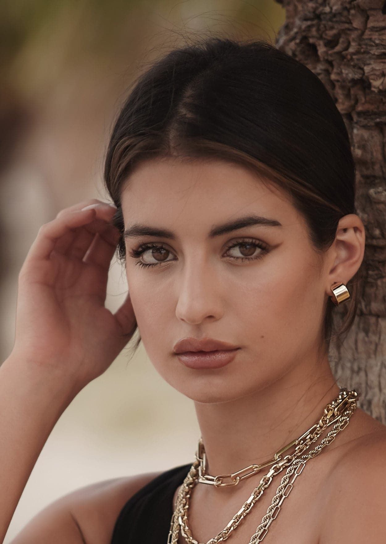 Woman showcasing Mini Skylar Hoops made of 14k gold rhodium and recycled brass hoops