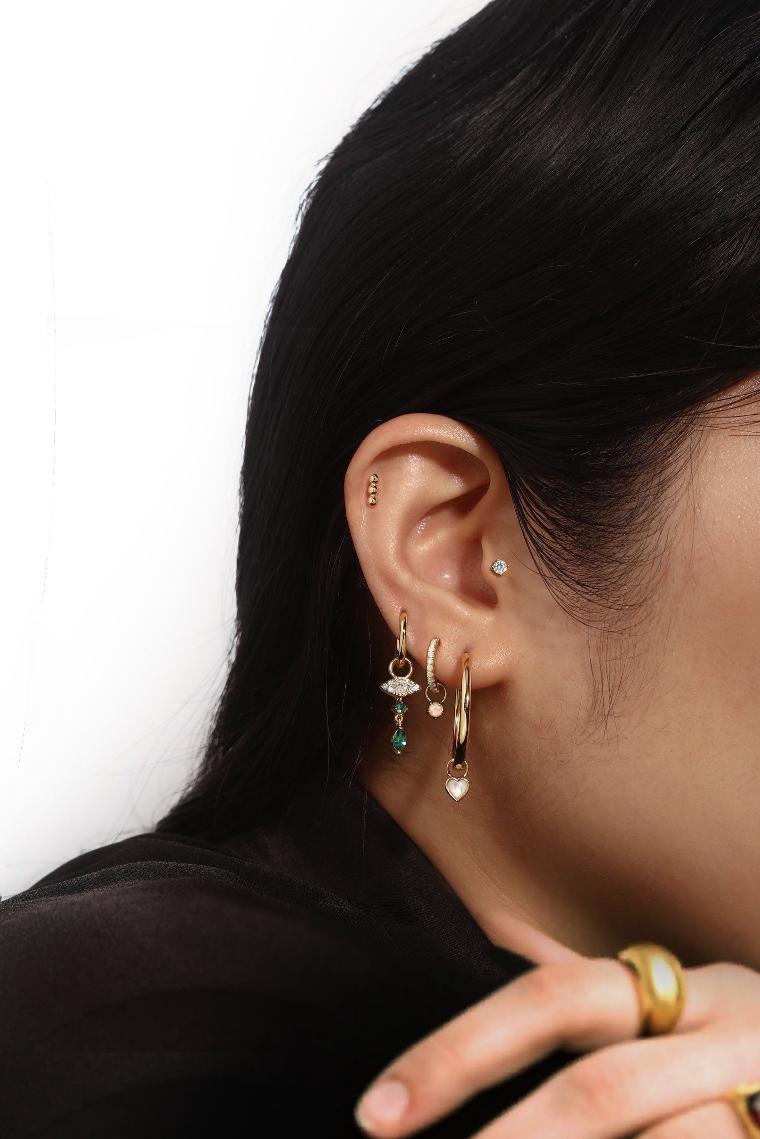 Ear with multiple gold earrings featuring 14k gold vermeil Opal Solitaire Hoop Charm