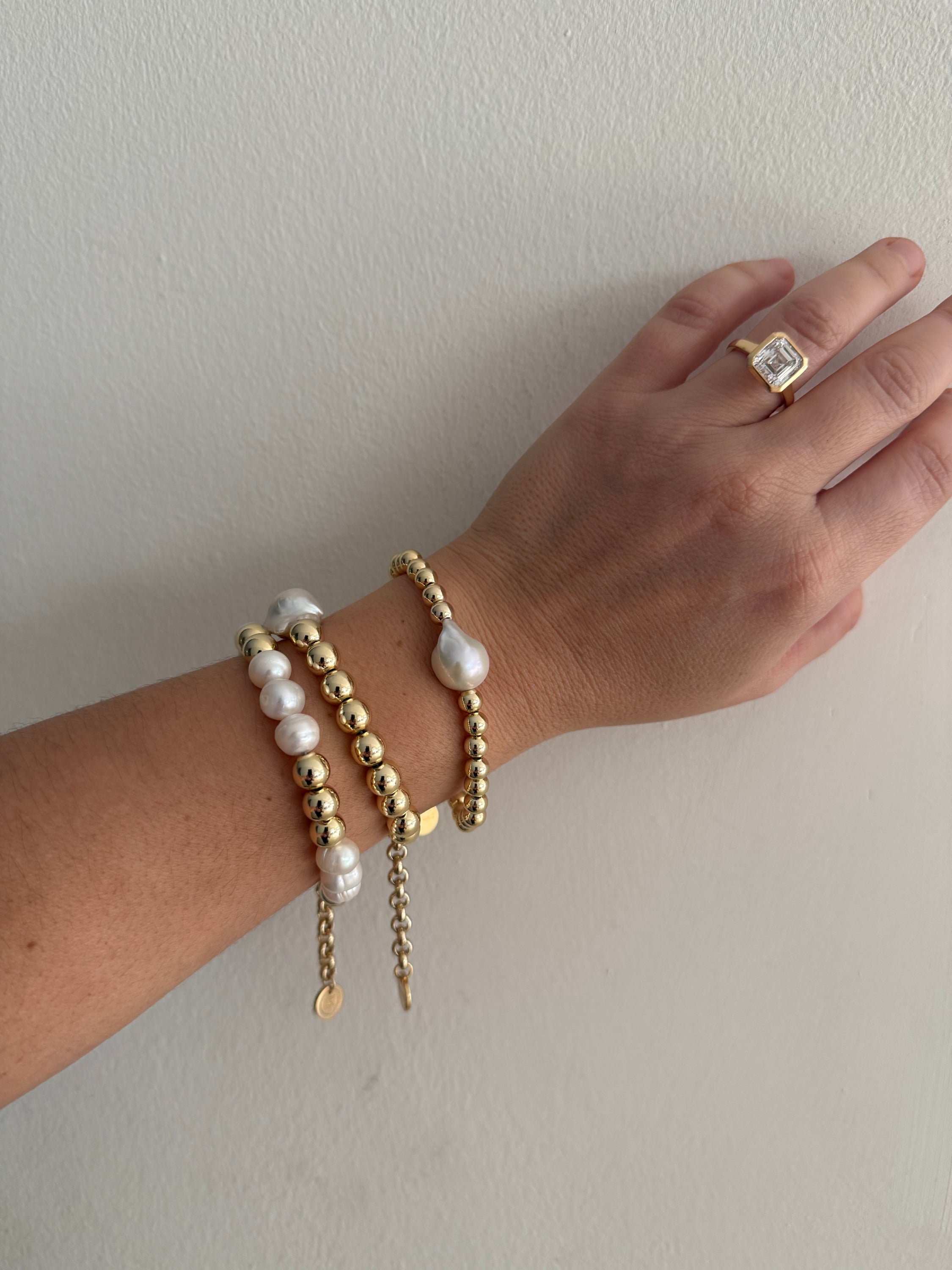 Woman’s hand showcasing a Petra Pearl And Bead Bracelet with elegant 14k gold jewelry