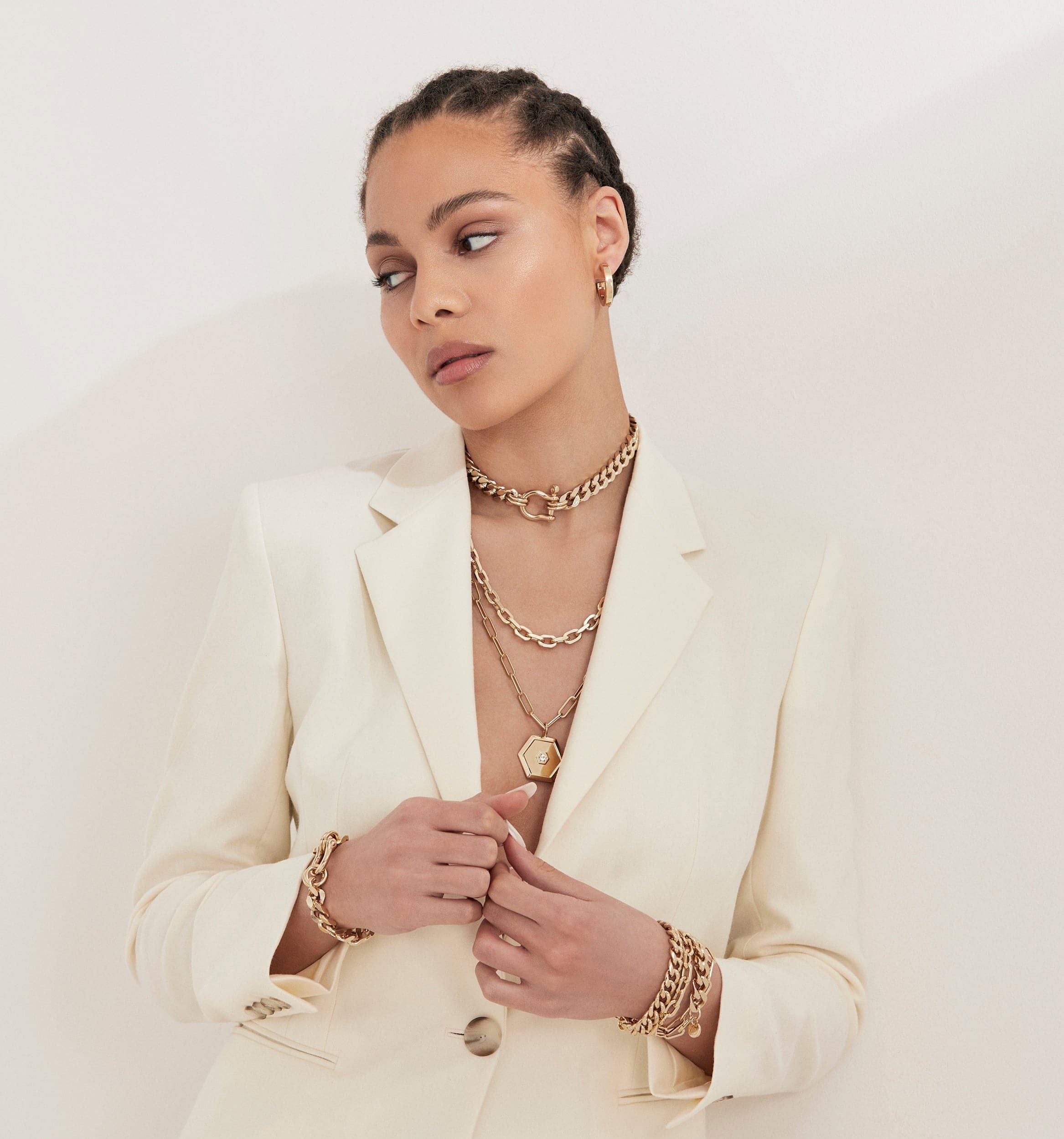 Woman in a white blazer showcasing the Roxy Bracelet made of recycled brass cuban links