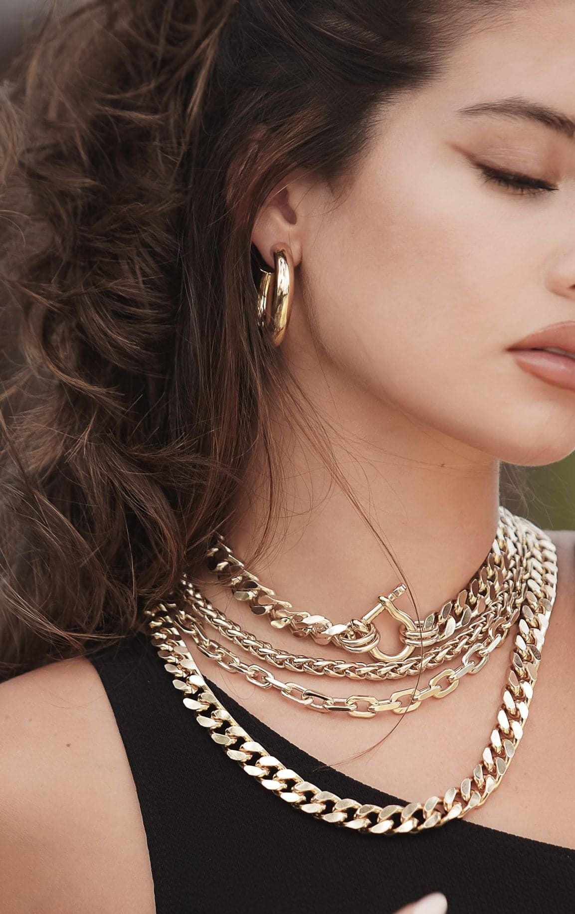 Woman showcasing the Roxy Necklace with a squared-off brass curb chain and horseshoe clasp