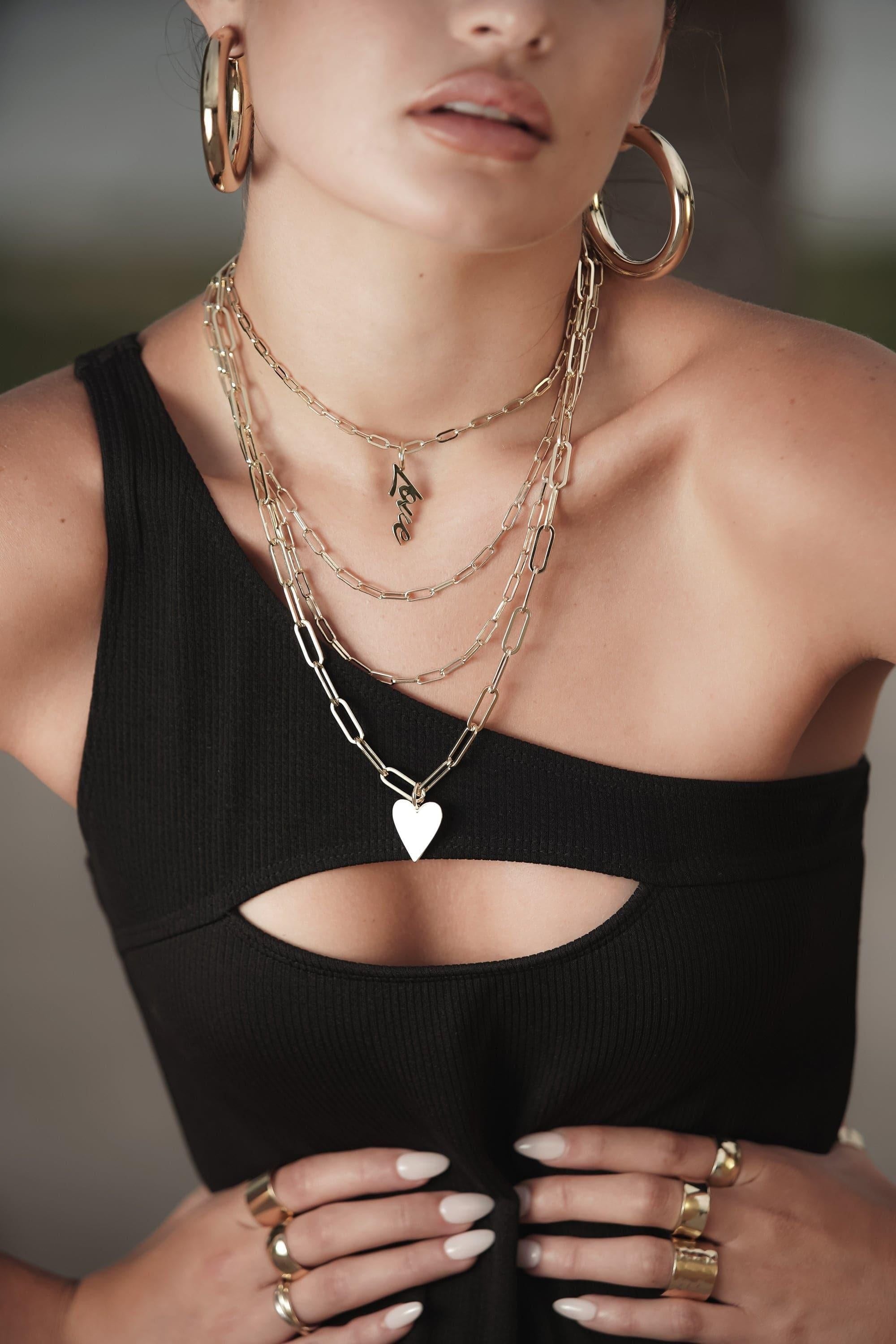 Woman showcasing Script Pendant Love on an elongated link chain, made of recycled brass plated