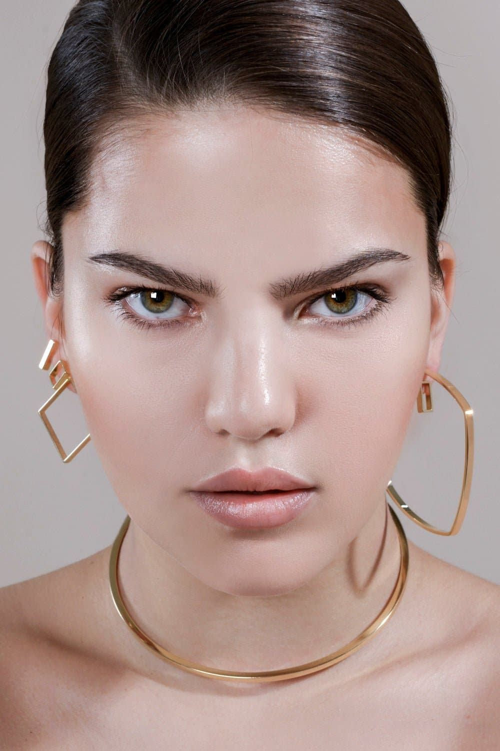 Woman showcasing bold square shaped hoops and elegant gold jewelry