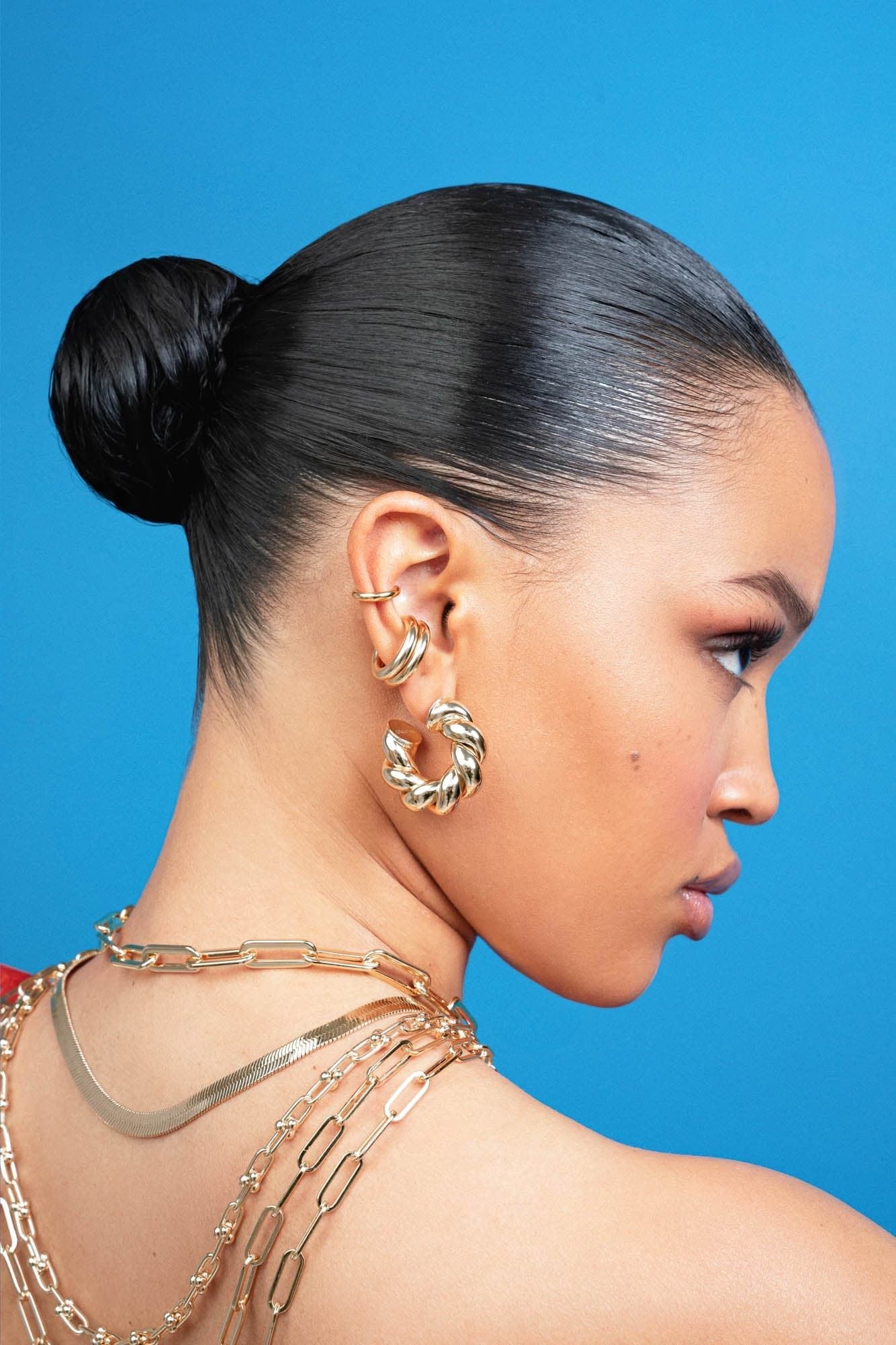 Woman wearing Tallulah Hoops made of recycled brass with a sleek bun hairstyle