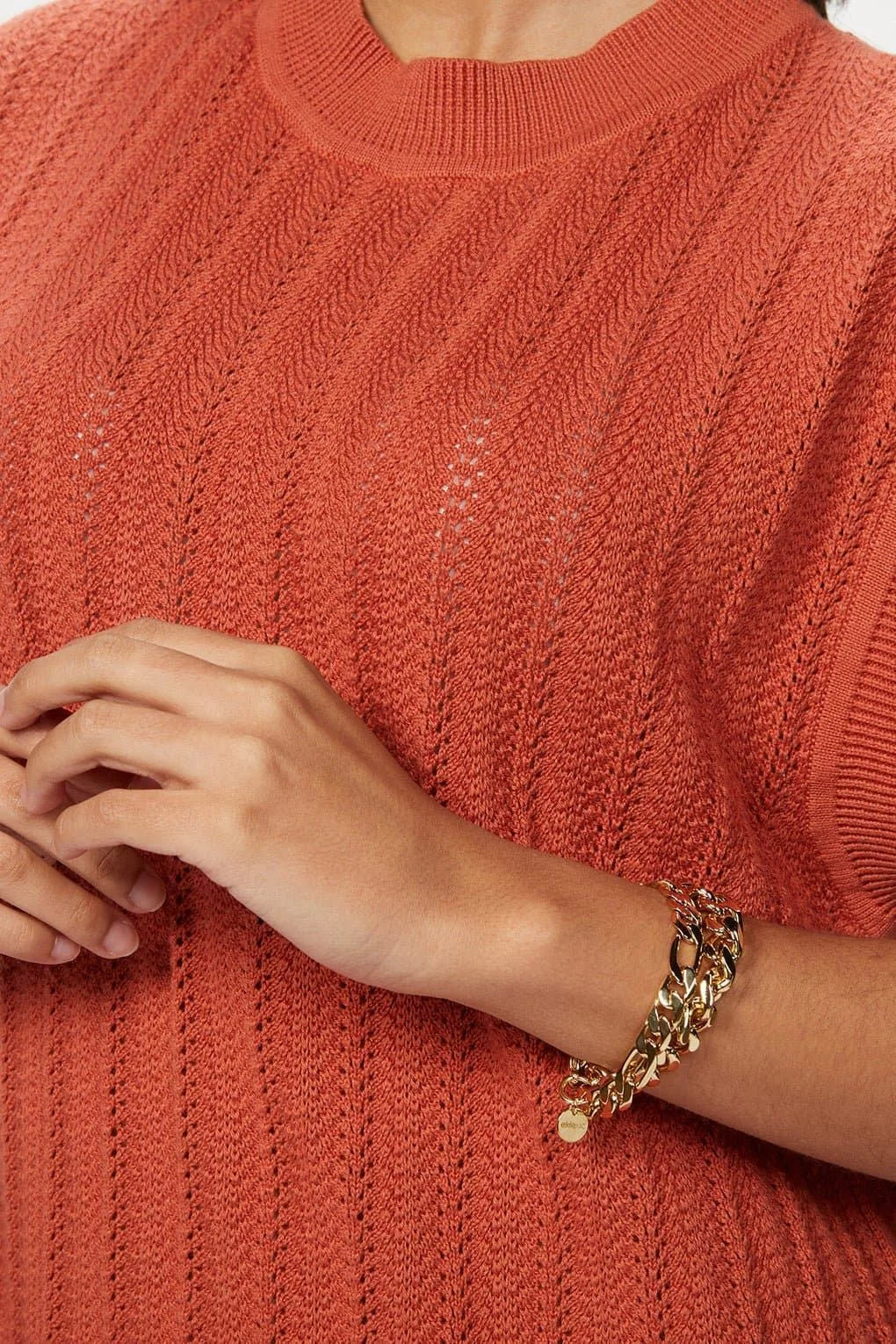 Rust-colored knit top with a gold chain bracelet for the Taraji Bracelet product shot
