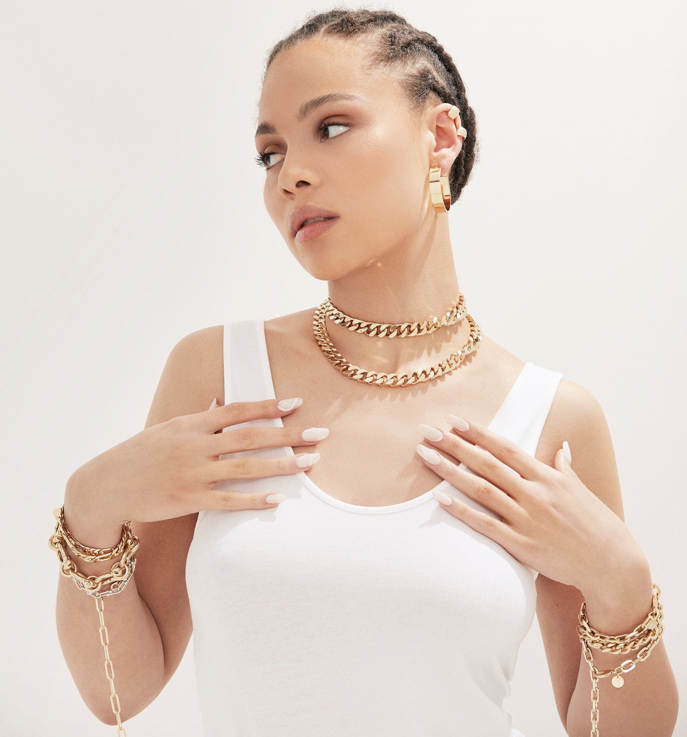 Woman showcasing the Taraji Necklace with brass Cuban link and rhodium-silver plating