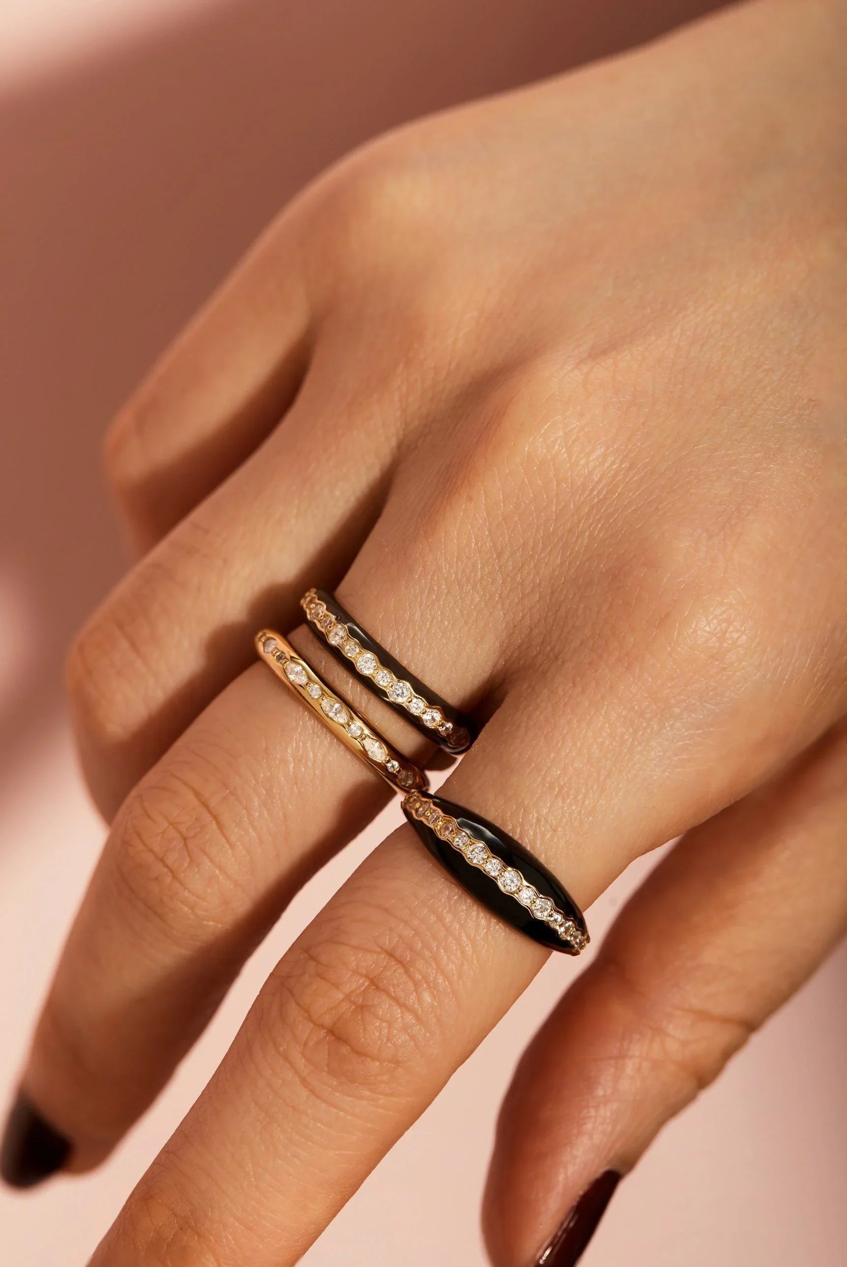 Hand with three rings featuring black enamel and CZ stones from the Thin Black Enamel & CZ Channel Ring collection