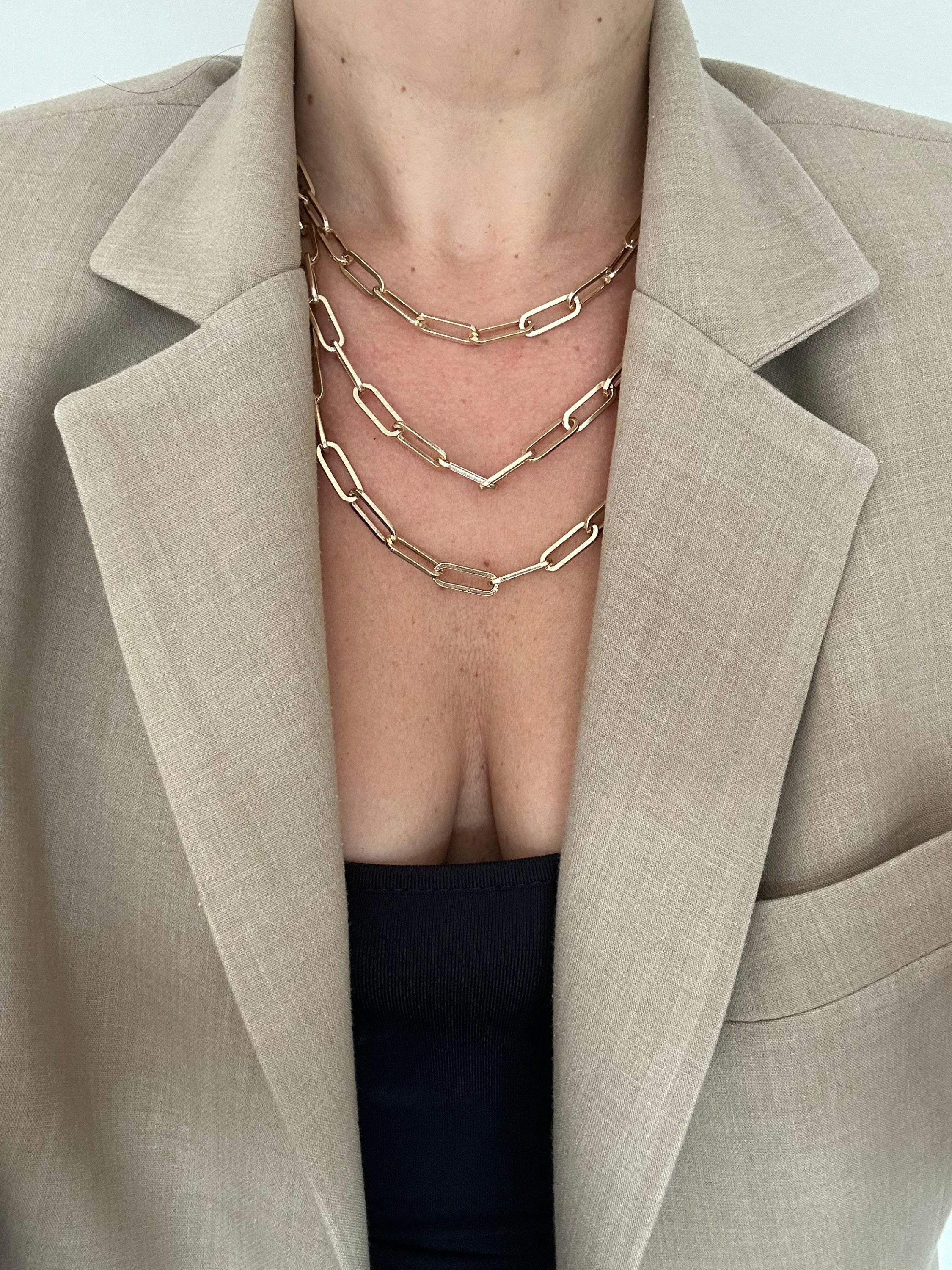 Gold chain layered necklace on a woman in a blazer featuring recycled brass large links