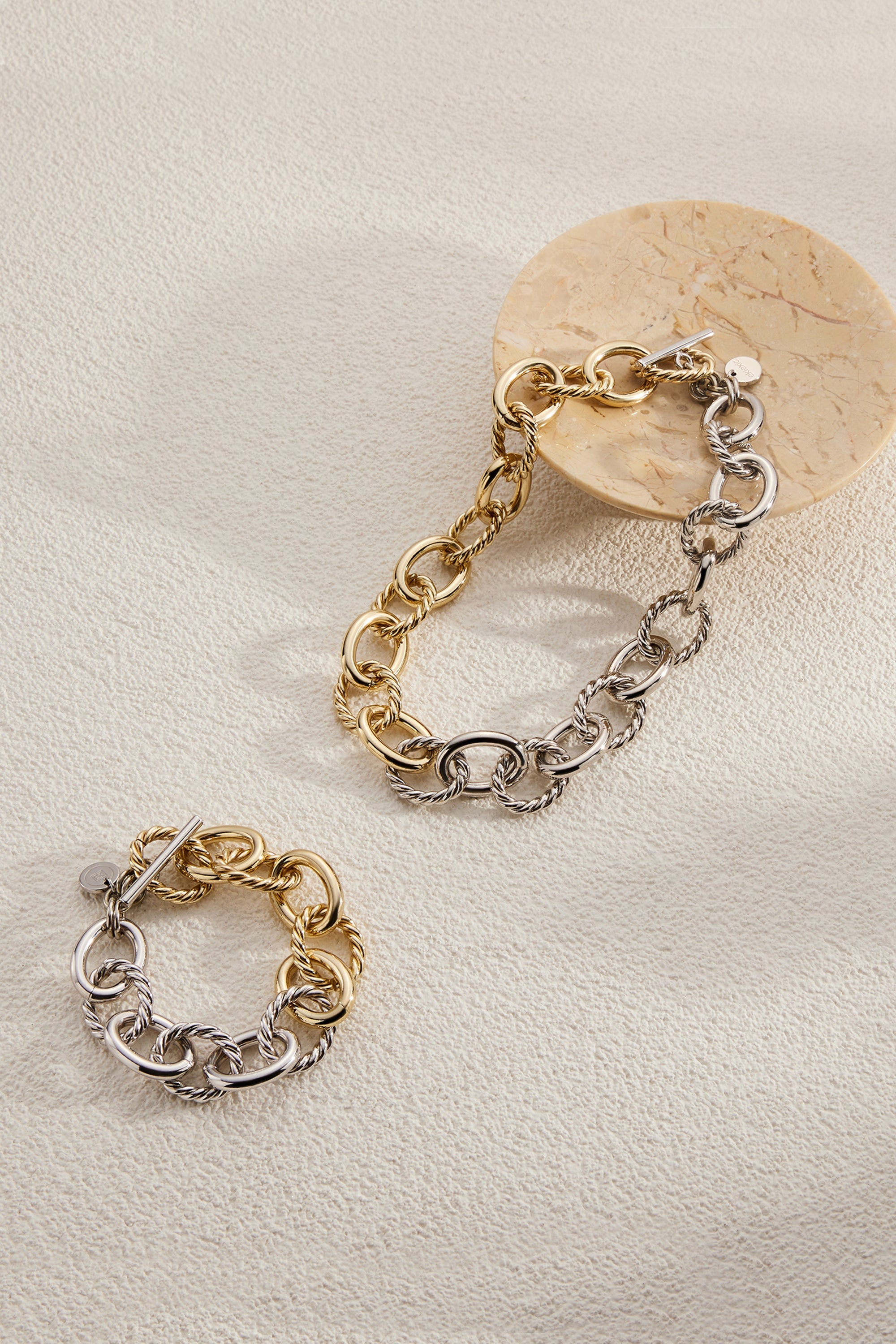 Two-tone chain bracelets in recycled brass and 14k gold with alternating twisted links