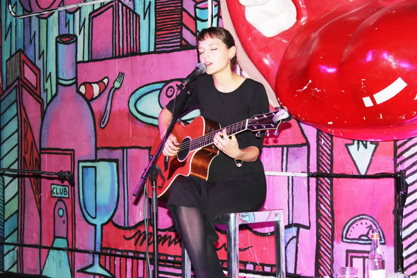 Woman playing acoustic guitar at US launch of album Highly Sensitive wearing EKLEXIC.