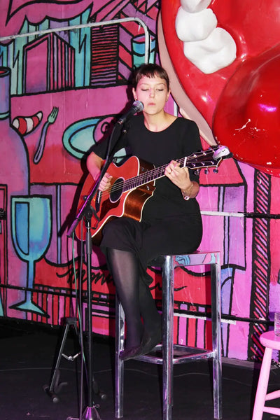 Woman playing guitar on stage during Highly Sensitive album launch in the US