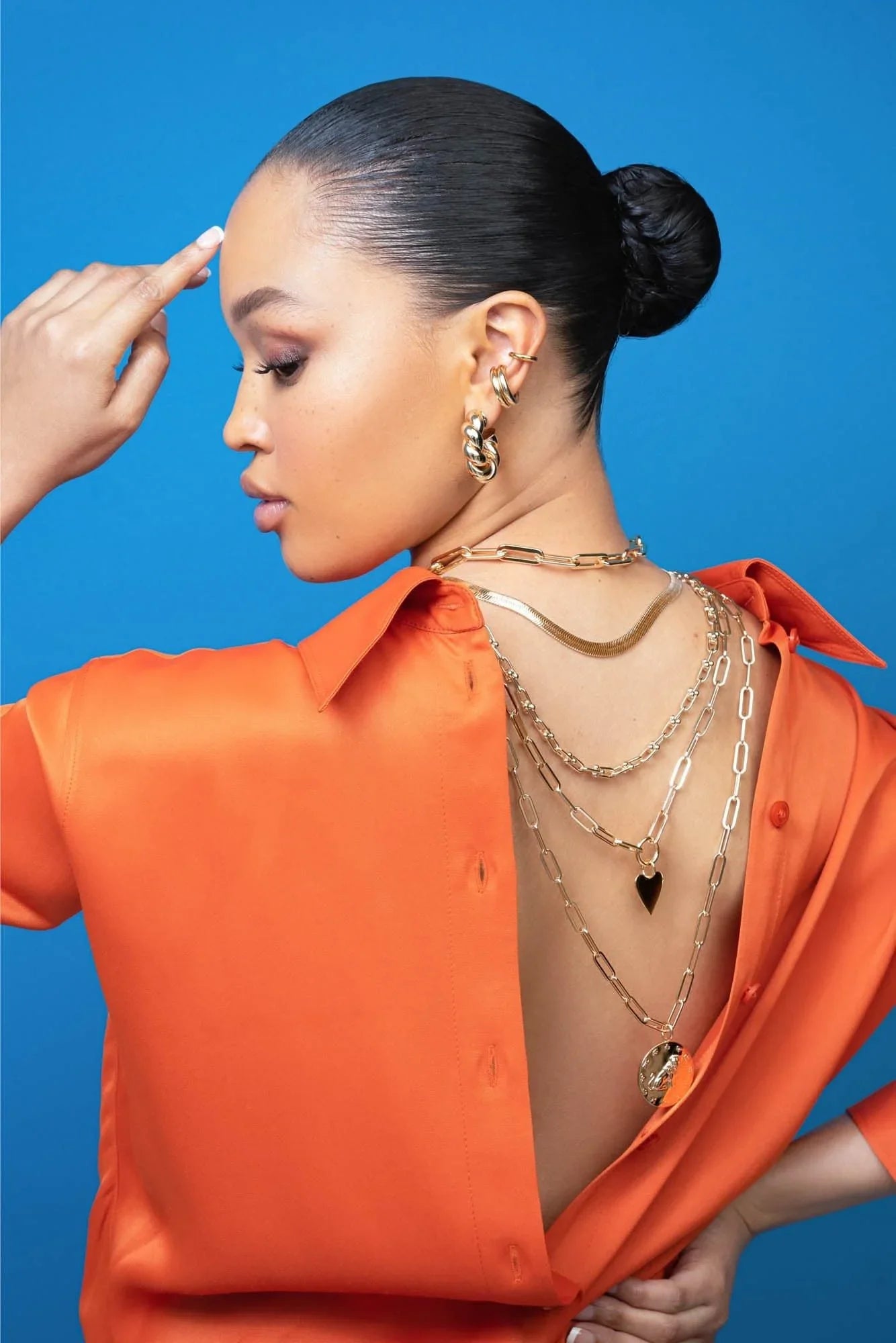 Woman in orange shirt wearing layered gold necklaces with Zodiac Pendant Aries